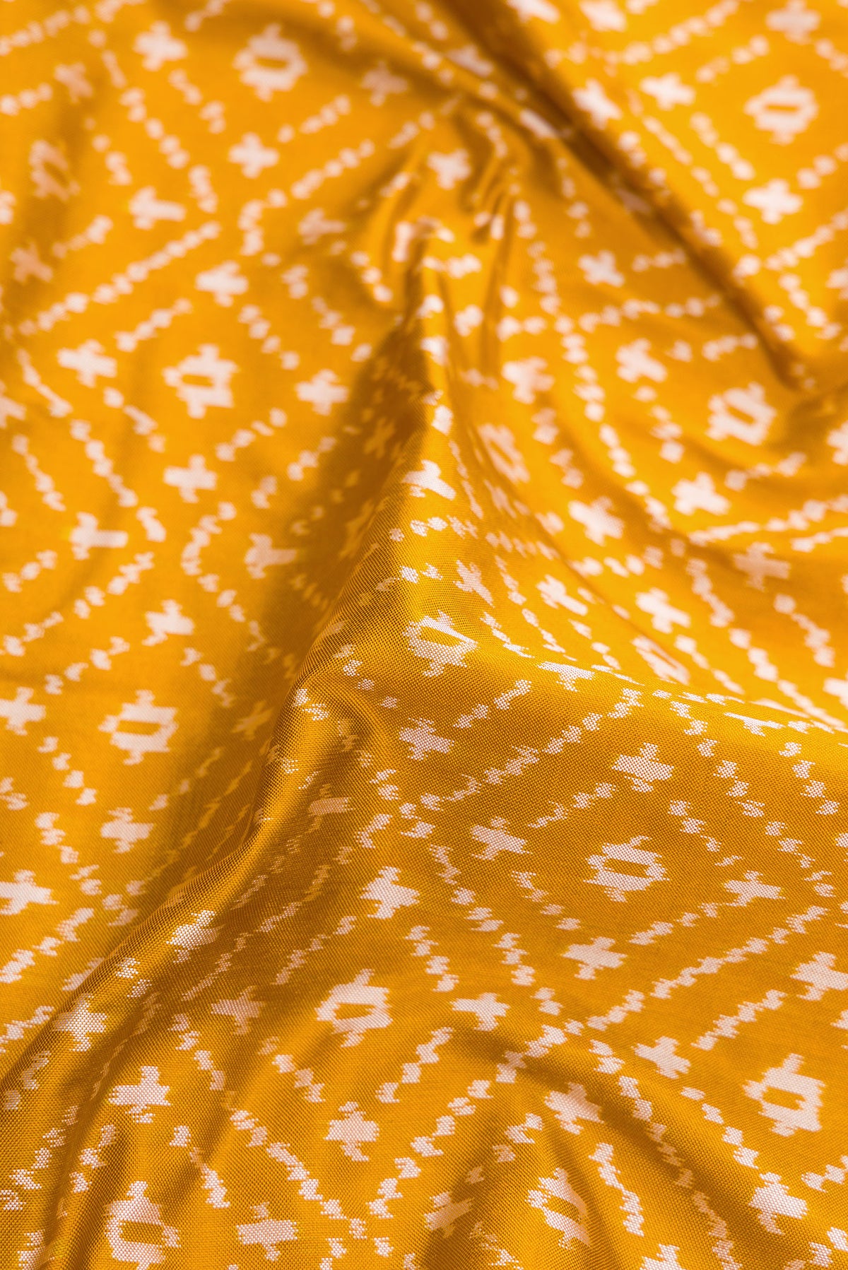 Close up of Mustard Dual Tone Double Ikat Nine Yards Saree with Ikat Print on the body and Zari Border.  displaying folds