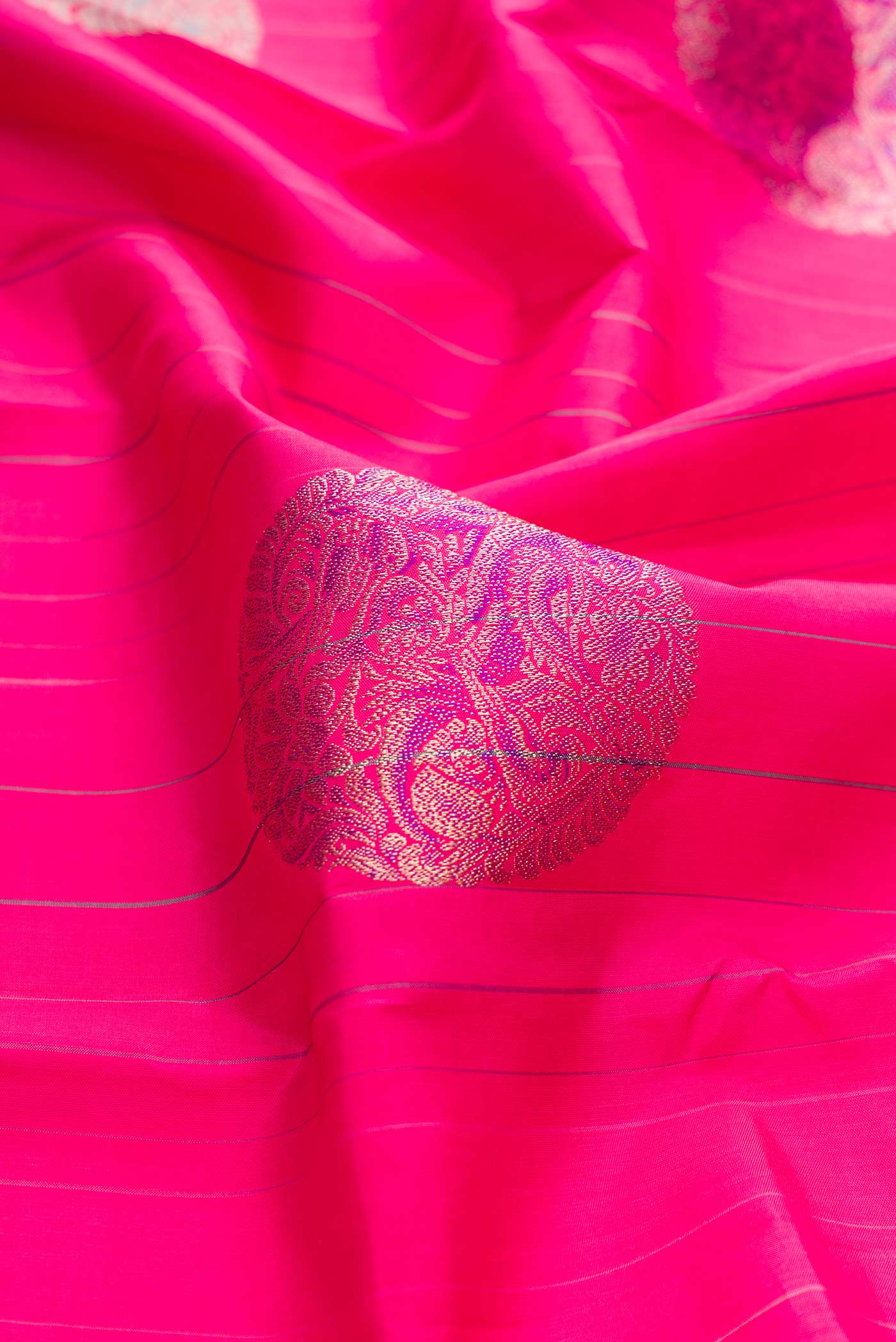 Close up of Dark Pink Dual Tone Kanchipuram Silk Saree with Zari And Thread Butta on the body and Without Border displaying folds