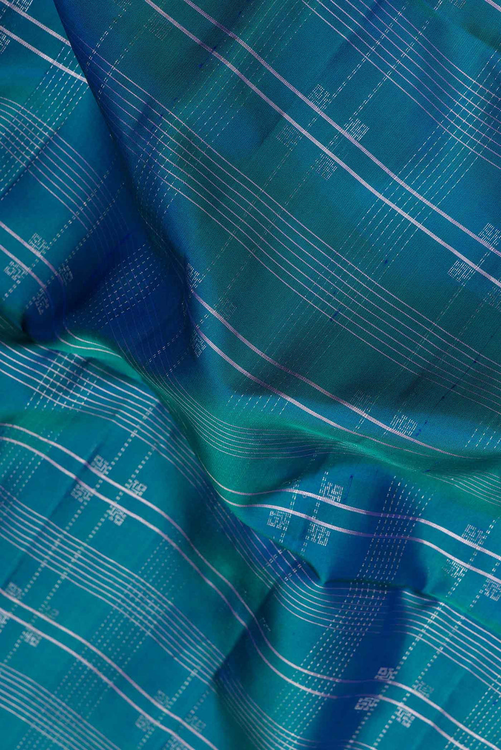 Close up of Peacock Blue Dual Tone Soft Silk Saree with Checked design on the body and Without Border.  displaying folds