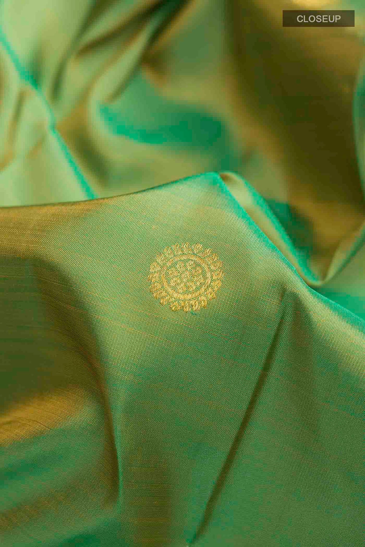 Close up of Green Kanchipuram Silk Saree with Zari Butta on the body and Zari Border displaying folds
