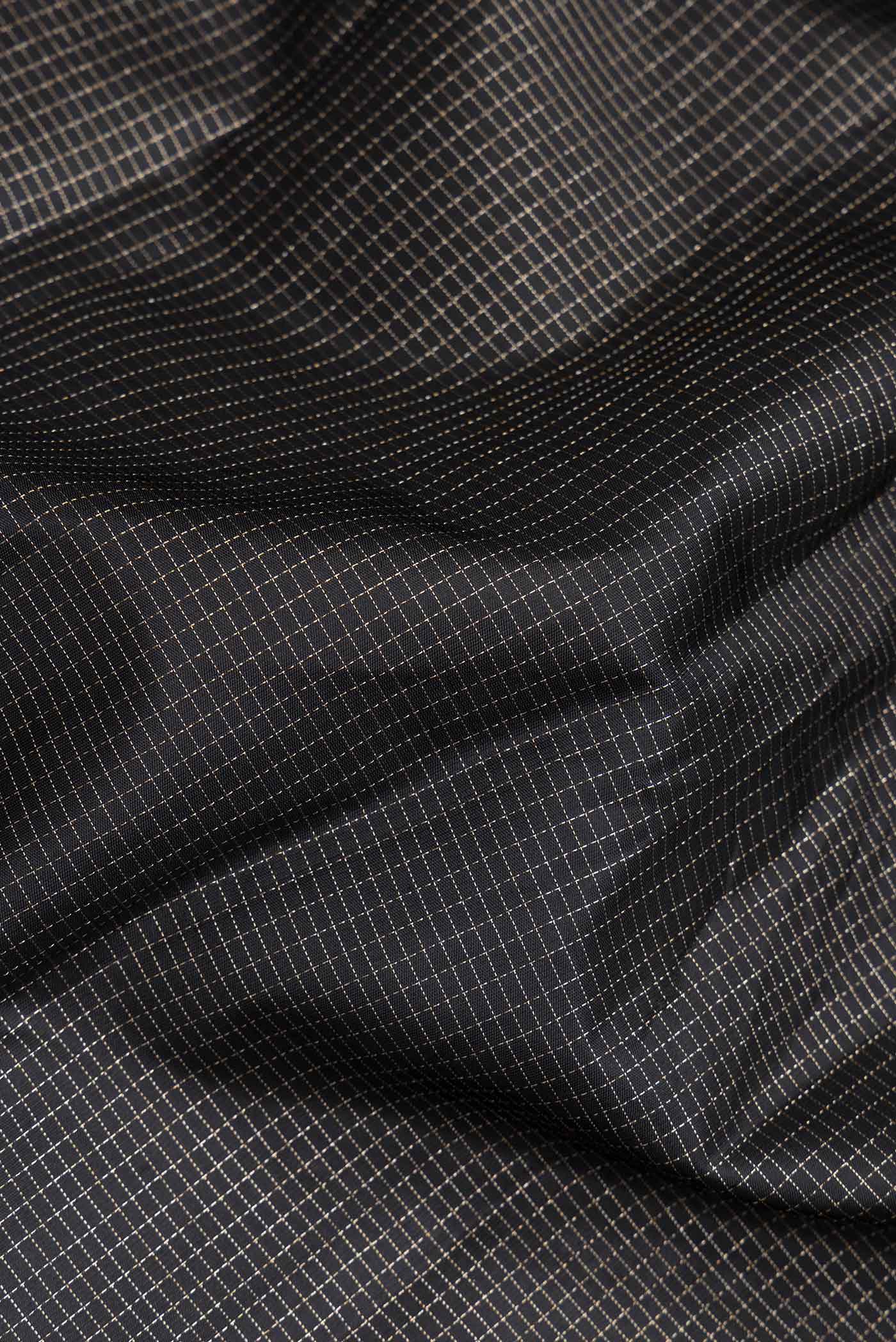 Close up of Black Dual Tone Kanchipuram Saree with Checked design on the body and Zari Border.  displaying folds