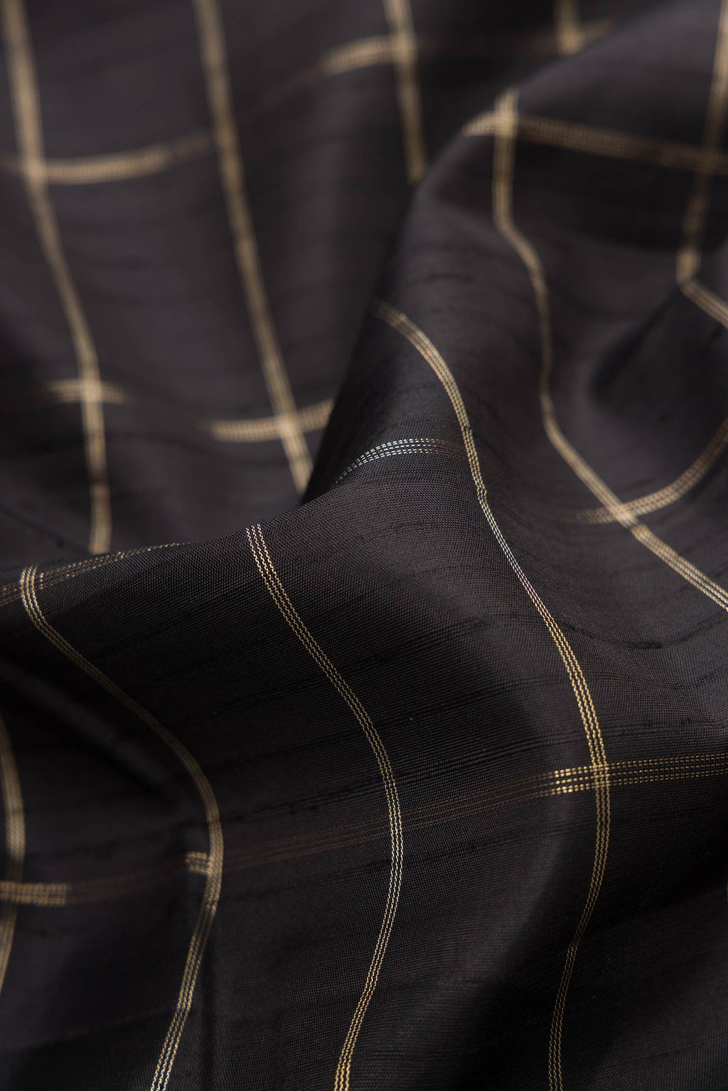 Close up of Black Dual Tone Kanchipuram Silk Saree with Checked design on the body and Zari Border displaying folds