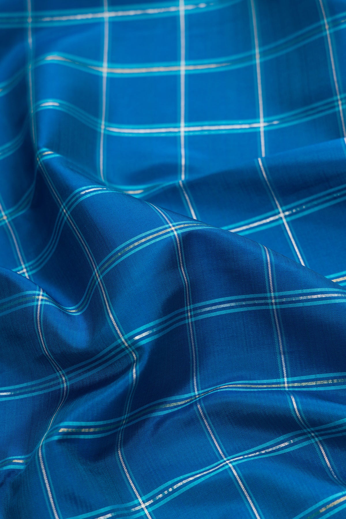 Close up of Pure Silk Pure Zari Peacock Blue Dual Tone Kanjivaram Saree with Checked design on the body and Zari Border.  displaying folds