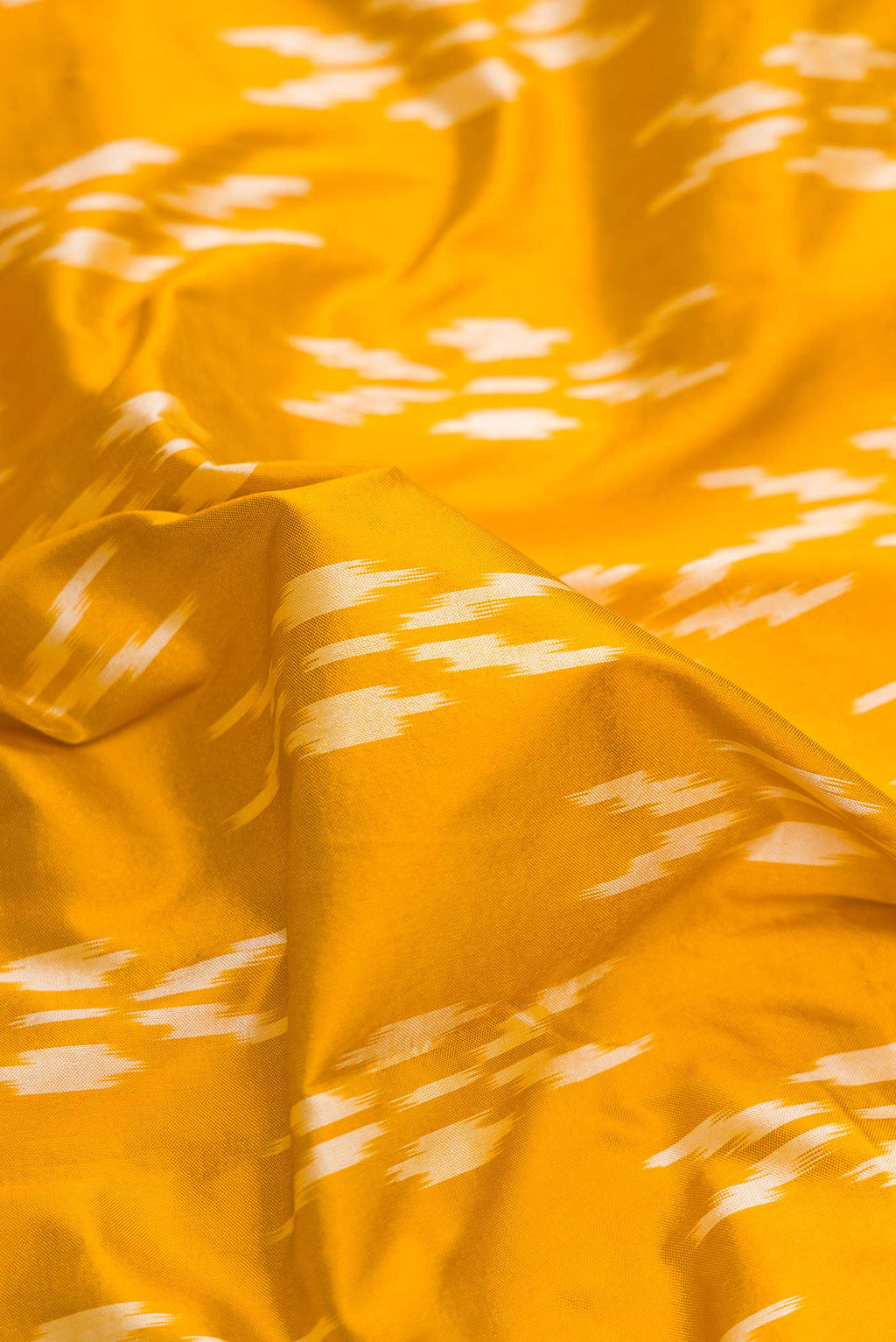 Close up of Mustard Dual Tone Double Ikat Saree with Ikat Print on the body and Ikat Border.  displaying folds