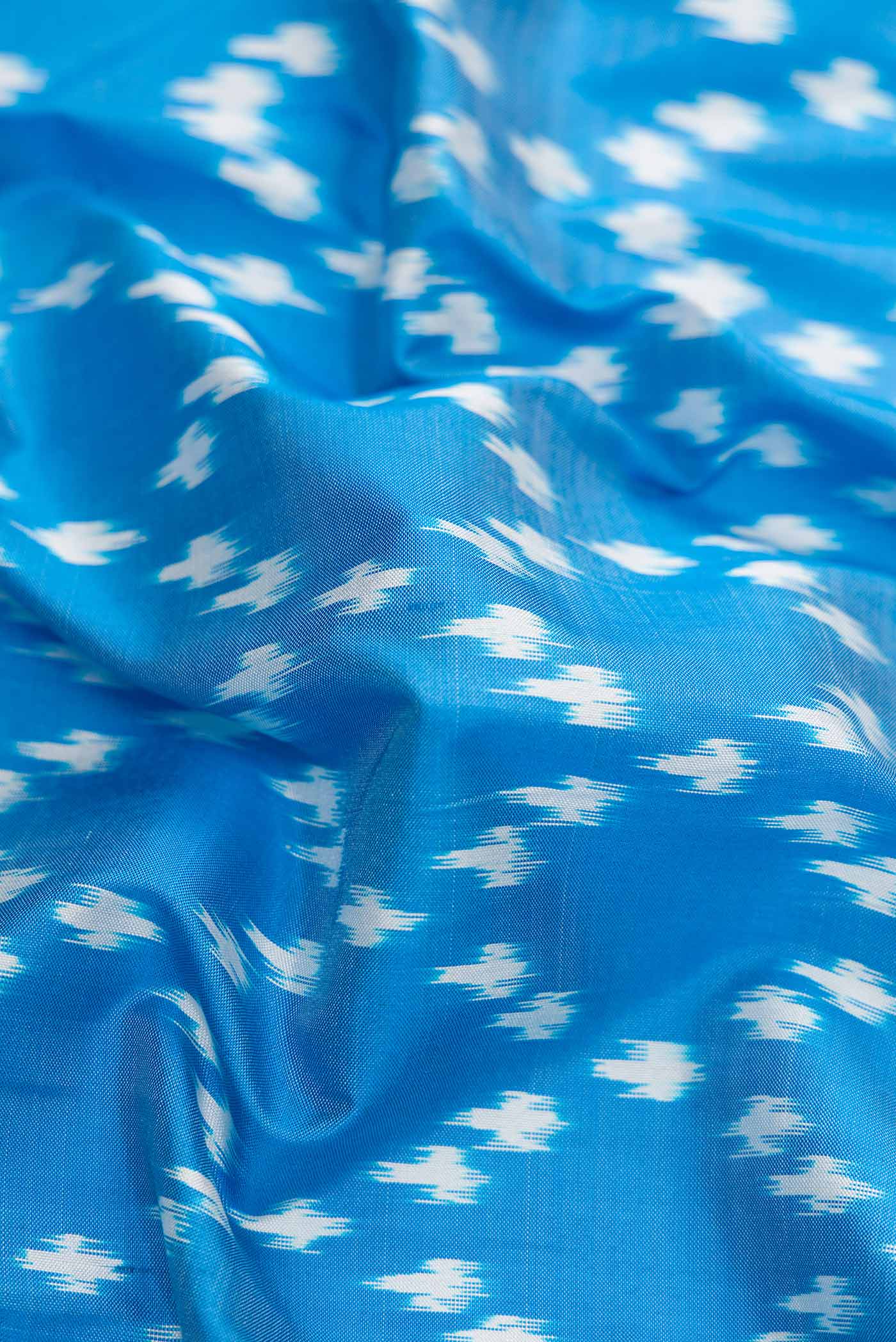 Close up of Peacock Blue Dual Tone Double Ikat Saree with Ikat Print on the body and Ikat Border.  displaying folds