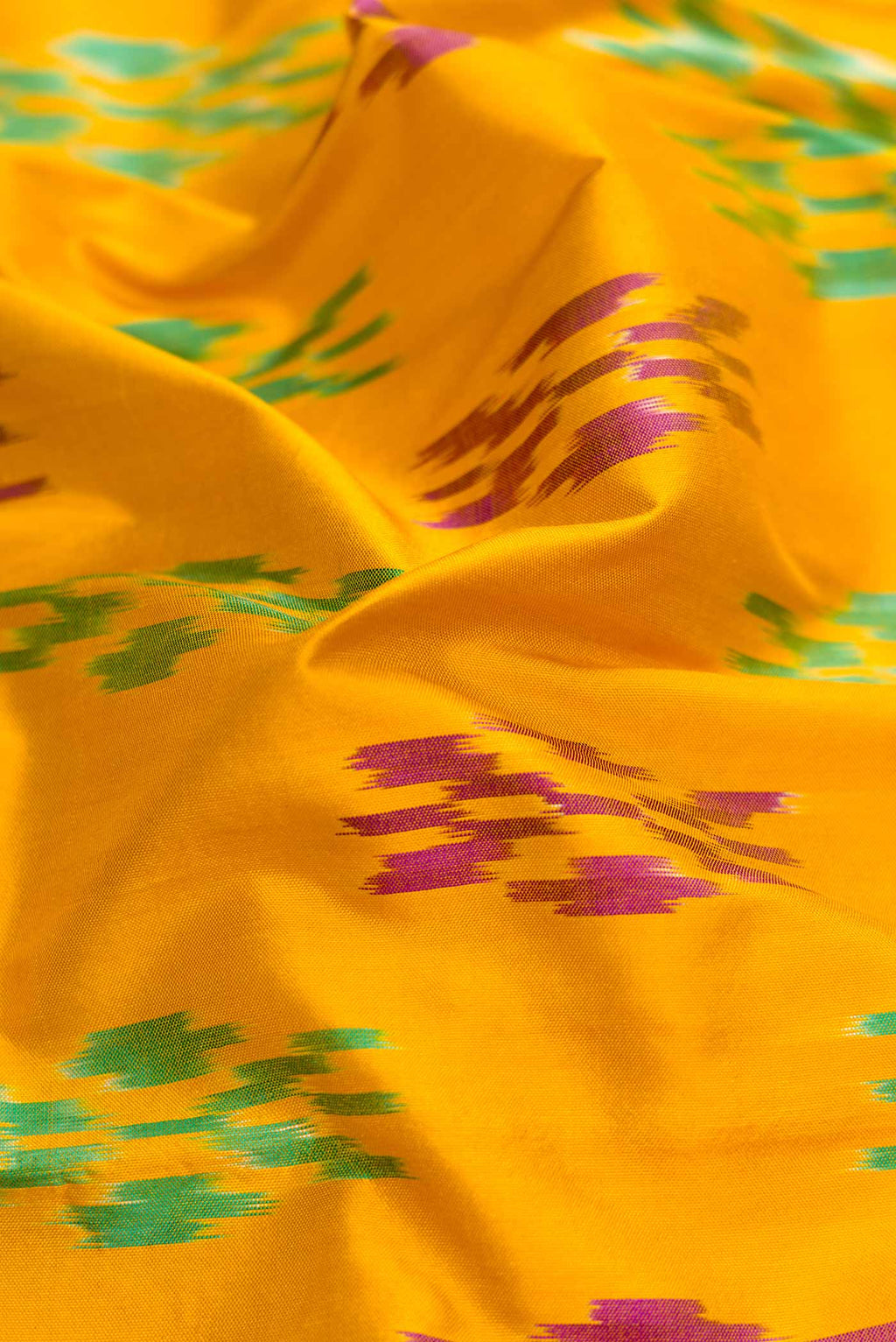 Close up of Mustard Dual Tone Double Ikat Saree with Ikat Print on the body and Ikat Border.  displaying folds