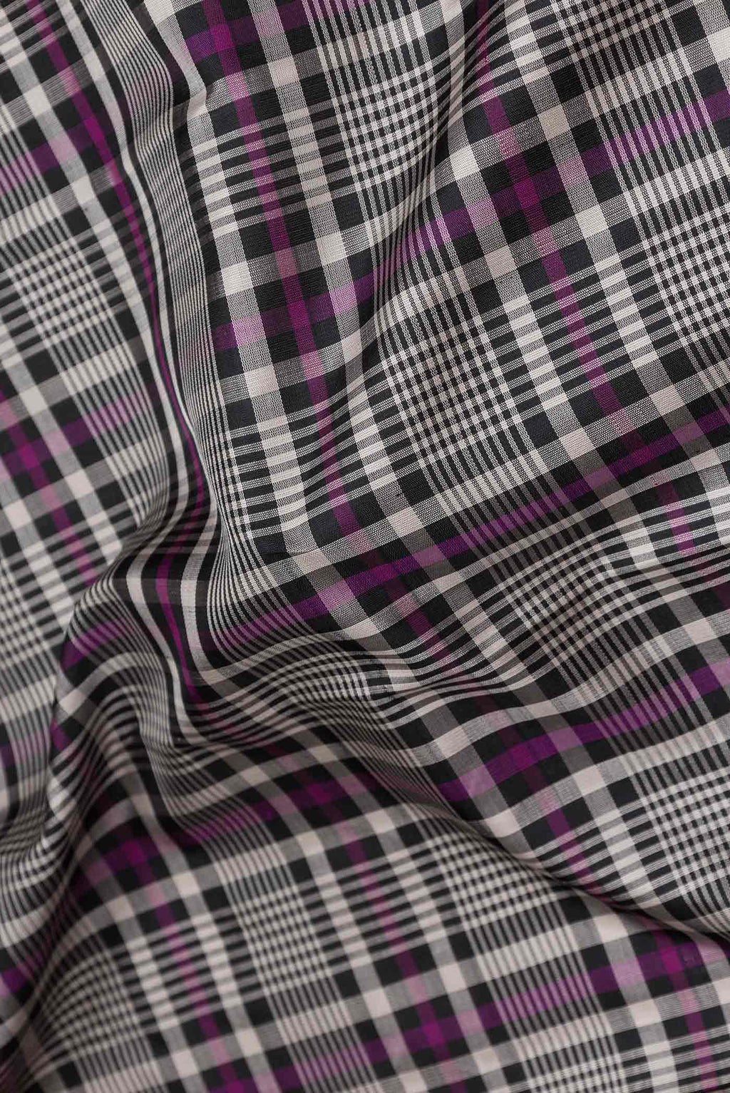 Close up of Black and Magenta Color Kanchipuram Silk Saree with Checked design on the body and Zari Border displaying folds