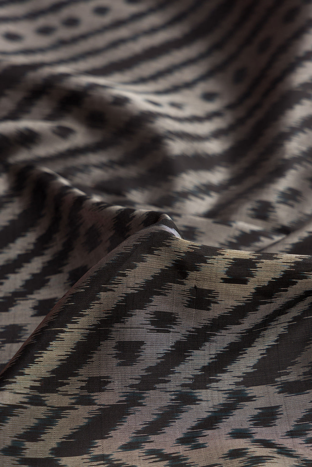 Close up of Black Dual Tone Soft Silk Saree with Ikat Print on the body and Ikat Border.  displaying folds