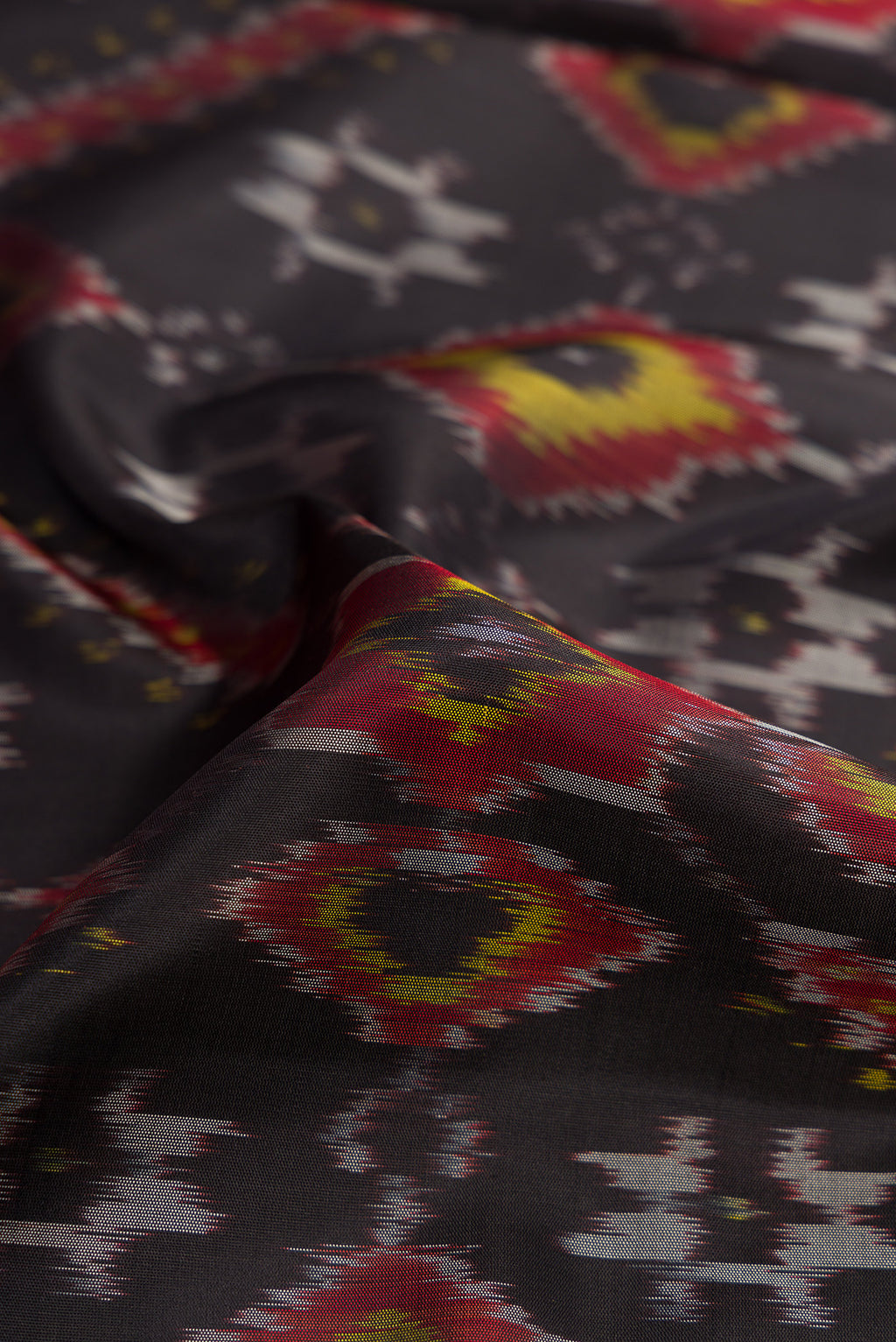 Close up of Black Dual Tone Soft Silk Saree with Ikat Print on the body and Ikat Border.  displaying folds