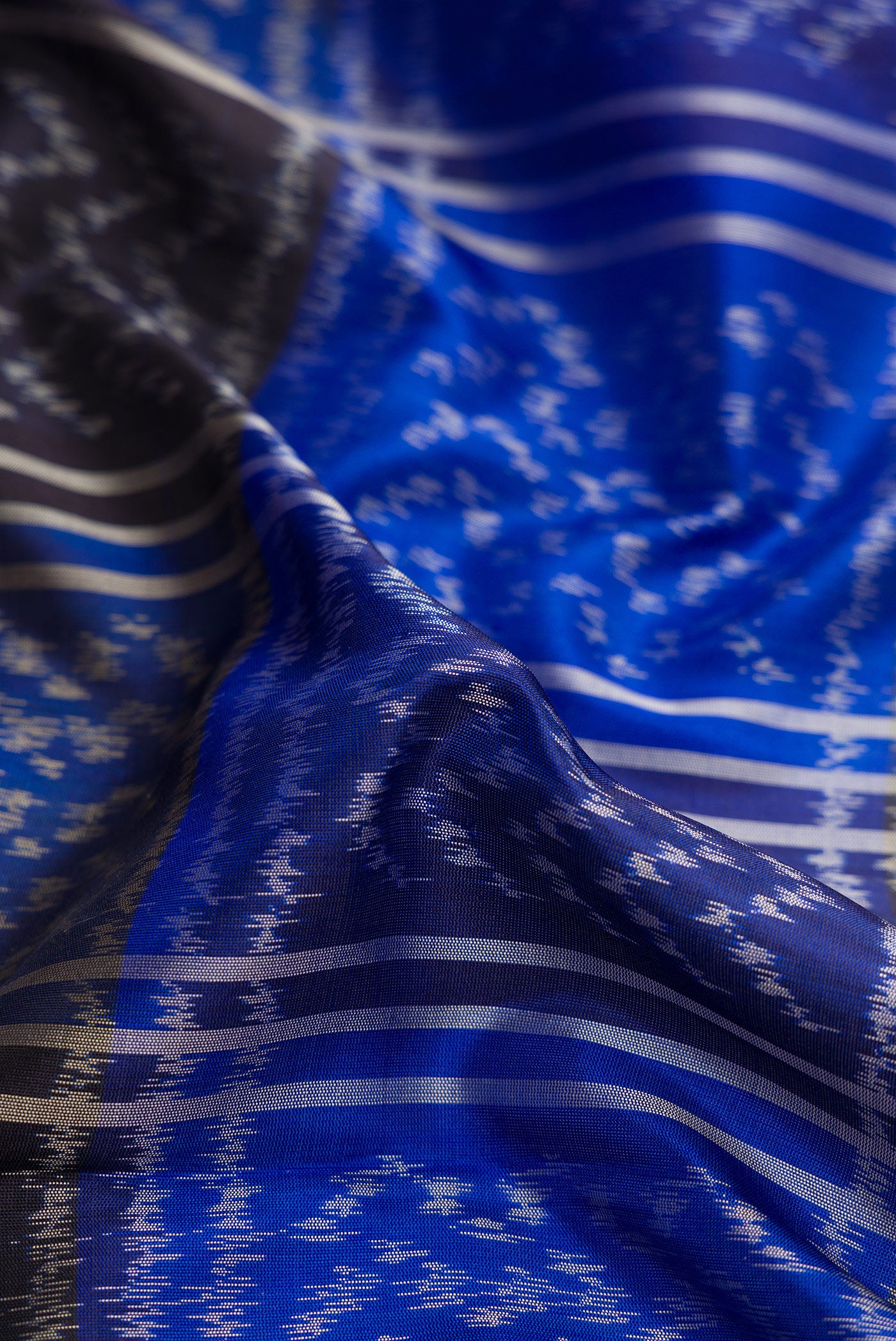 Close up of Royal Blue Dual Tone Soft Silk Saree with Ikat Print on the body and Zari Border.  displaying folds