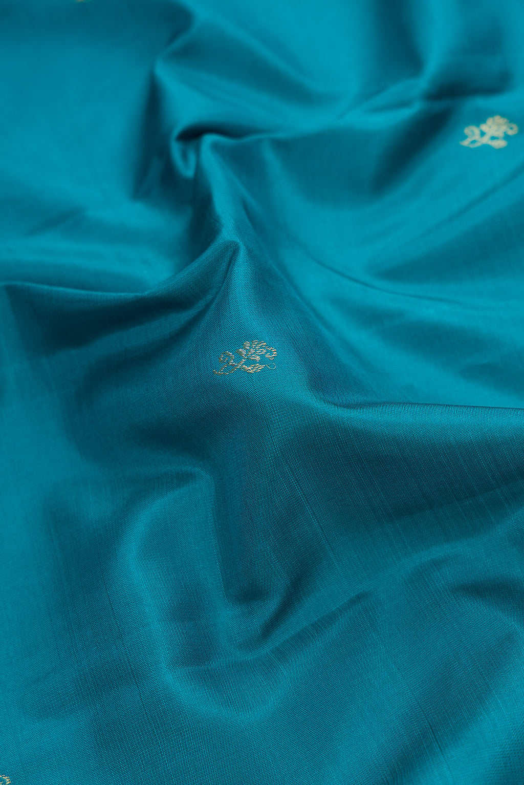 Close up of Peacock Blue Dual Tone Kanjivaram Silk Saree with Zari Butta on the body and Fancy Border.  displaying folds