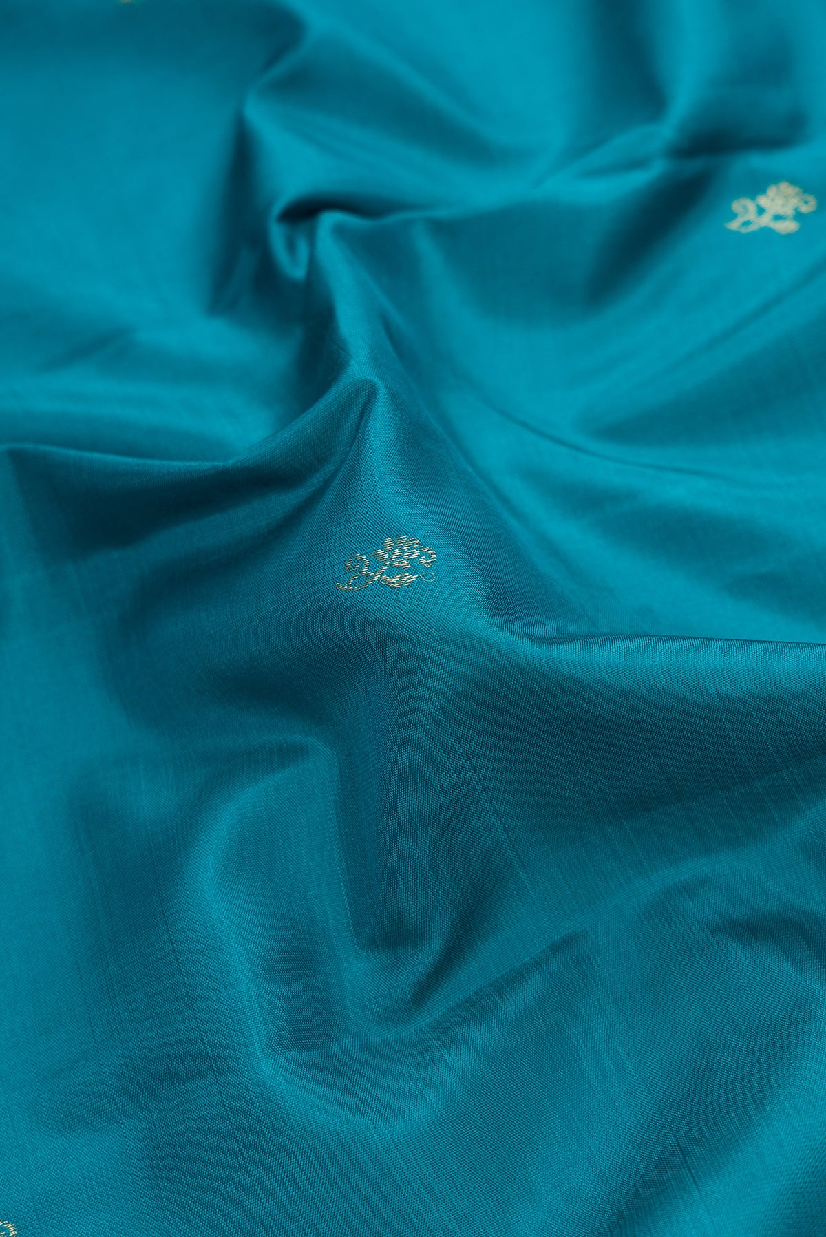 Close up of Peacock Blue Dual Tone Kanjivaram Silk Saree with Zari Butta on the body and Fancy Border.  displaying folds