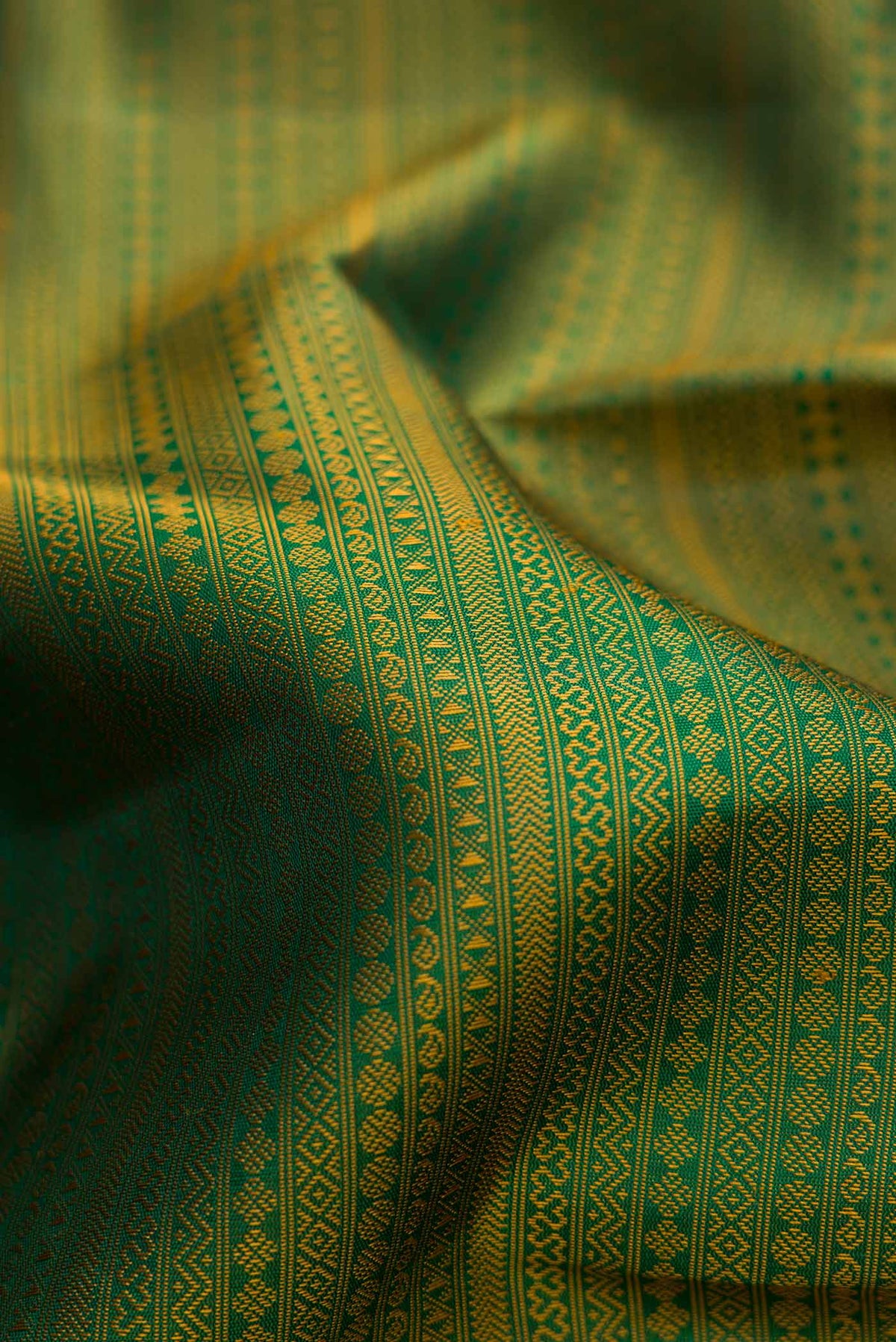Close up of Pure Silk Pure Zari Green Dual Tone Kanjivaram Saree with Jacquard design on the body and Zari Border.  displaying folds