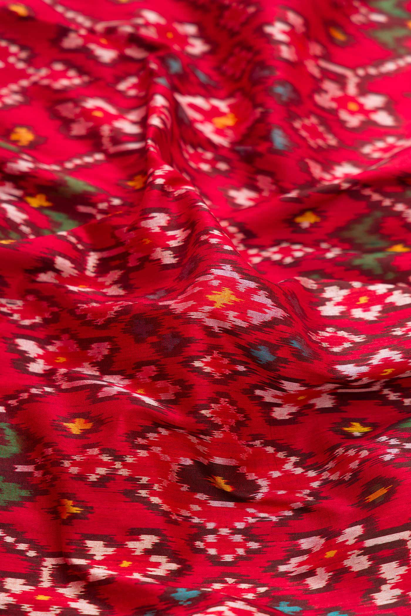 Close up of Pure Silk Pure Zari Red Dual Tone Double Ikat Saree with Ikat Print on the body and Fancy Border displaying folds