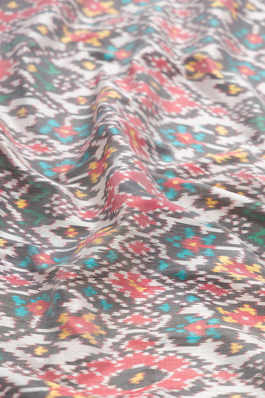 Close up of Grey Dual Tone Double Ikat Saree with Ikat Print on the body and Zari Border.  displaying folds