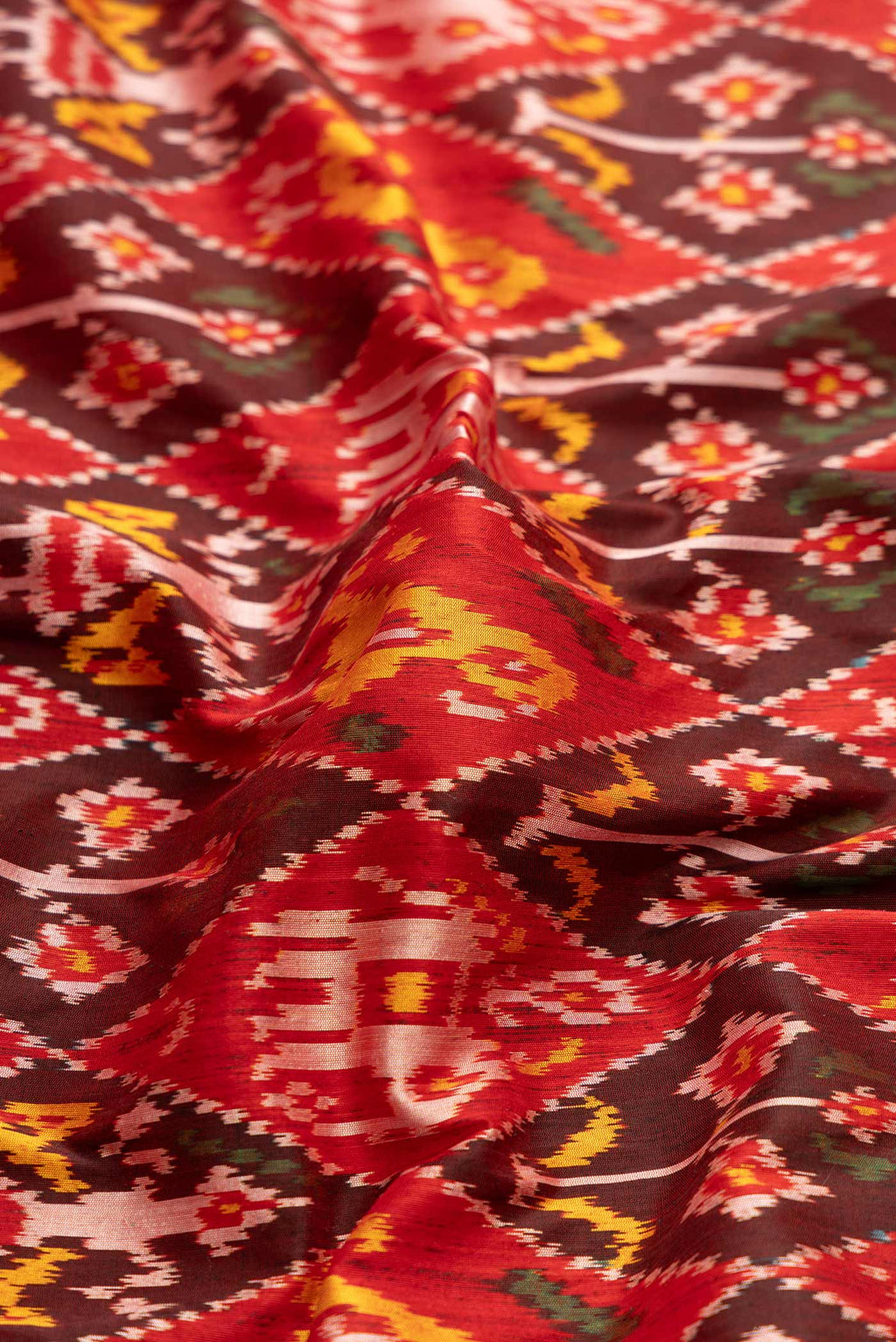 Close up of Pure Silk Pure Zari Red Dual Tone Double Ikat Saree with Ikat Print on the body and Fancy Border displaying folds