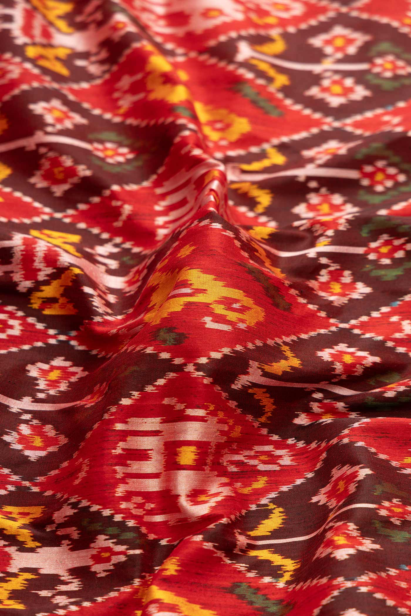 Close up of Pure Silk Pure Zari Red Dual Tone Double Ikat Saree with Ikat Print on the body and Fancy Border displaying folds