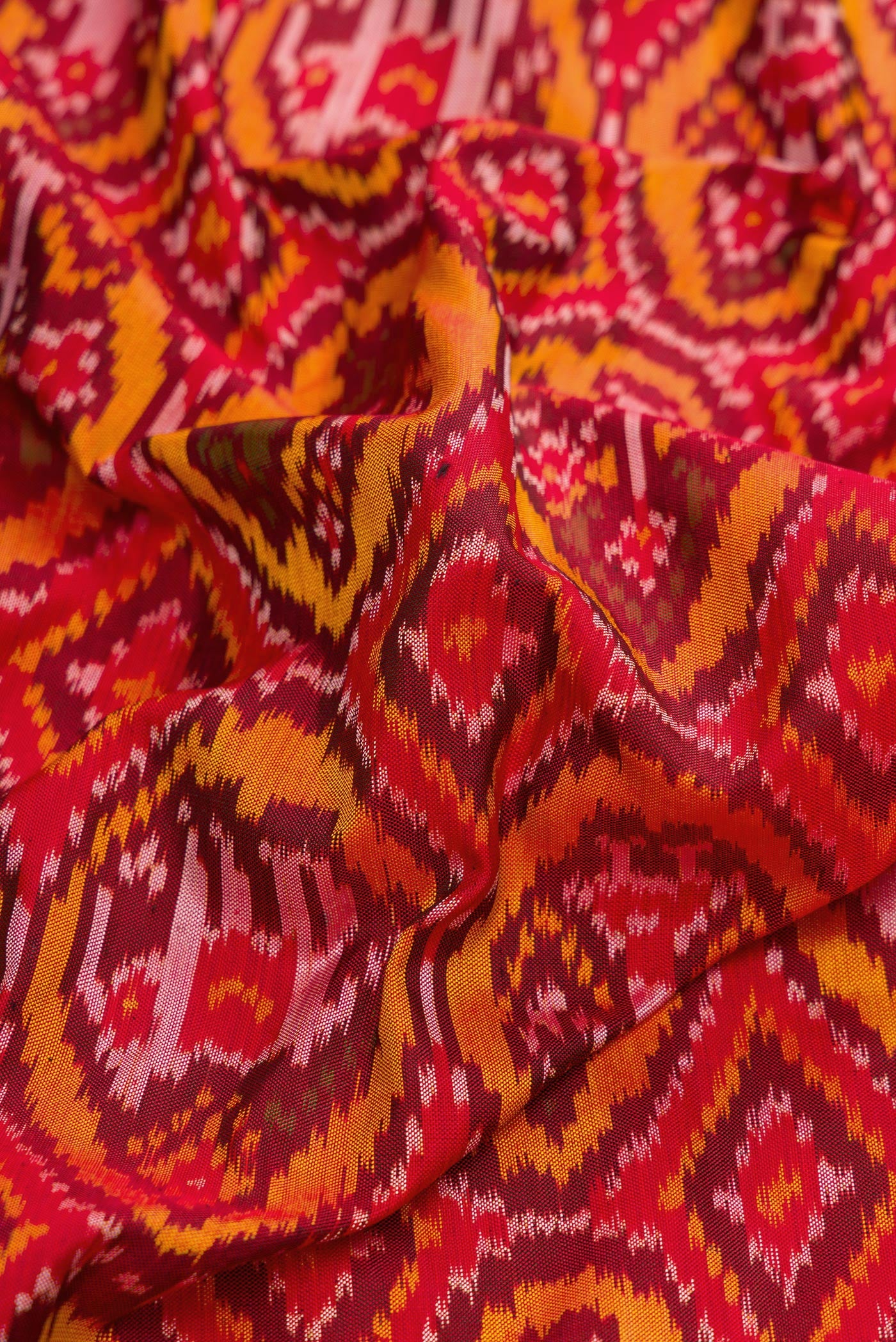 Close up of Red Dual Tone Double Ikat Saree with Ikat Print on the body and Zari Border.  displaying folds