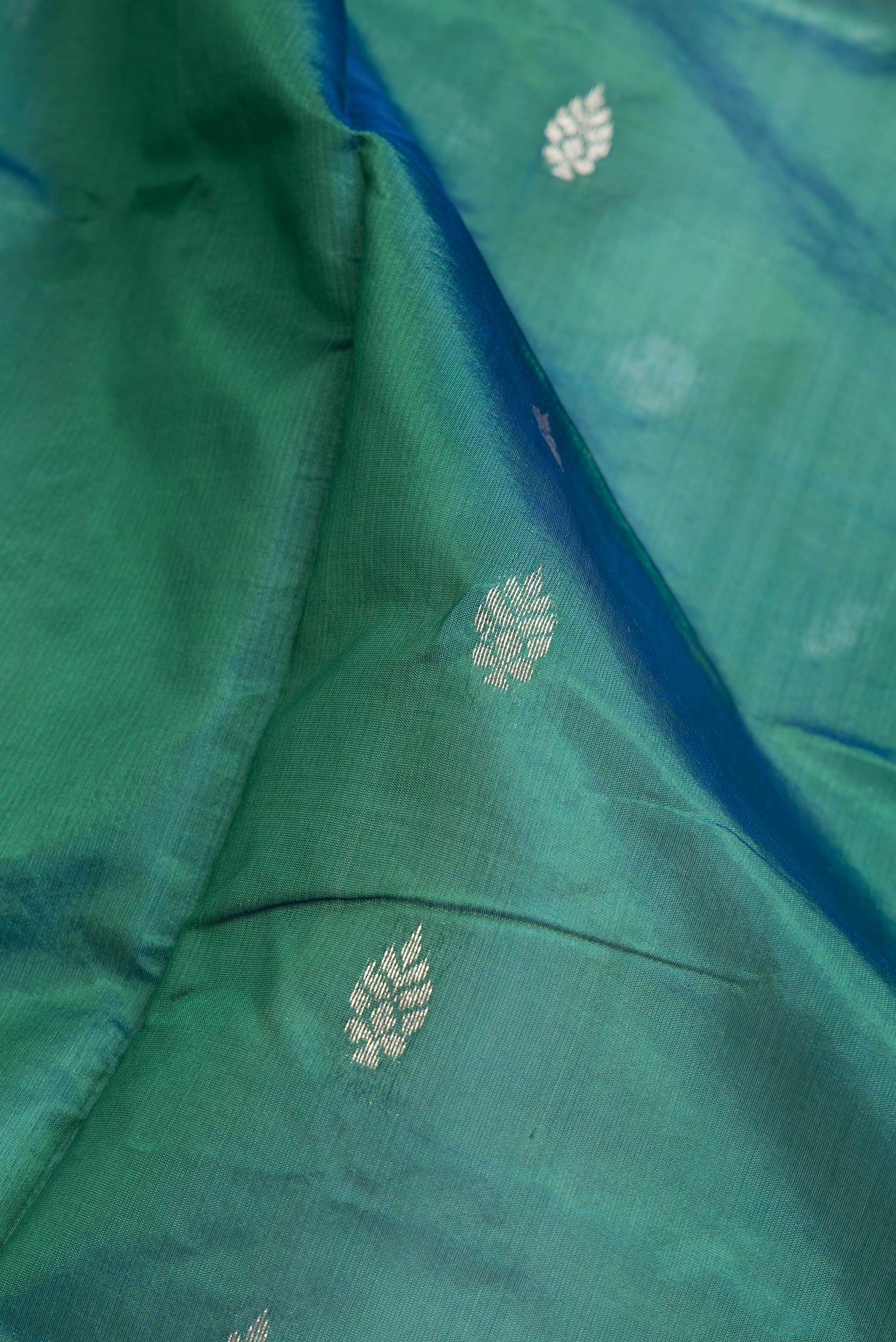 Close up of Green Dual Tone Banarasi Silk Saree with Zari Butta on the body and Zari Border.  displaying folds