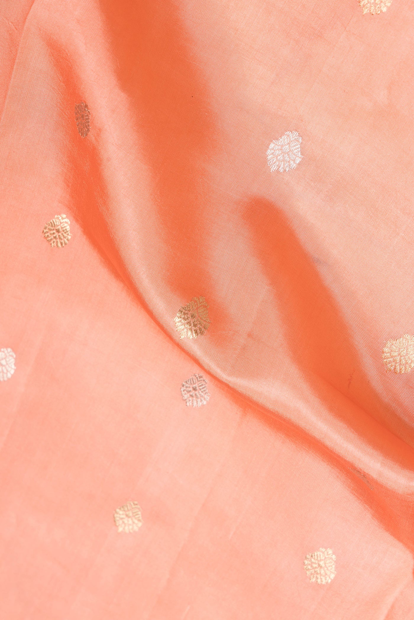 Close up of Peach Dual Tone Banarasi Silk Saree with Zari Butta on the body and Fancy Border.  displaying folds