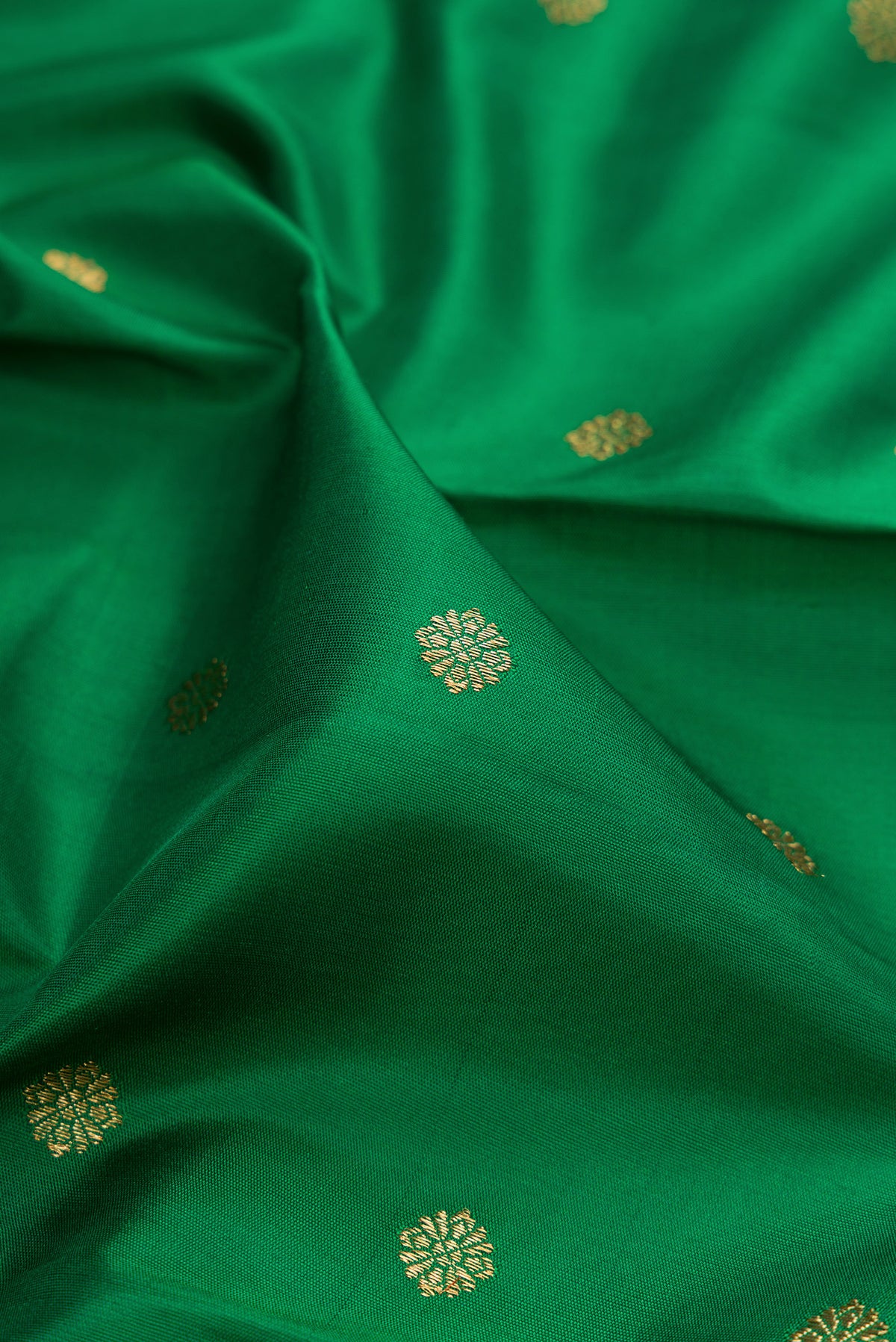 Close up of Pure Silk Pure Zari Green Kanjivaram Saree with Zari Butta on the body and Zari Border.  displaying folds
