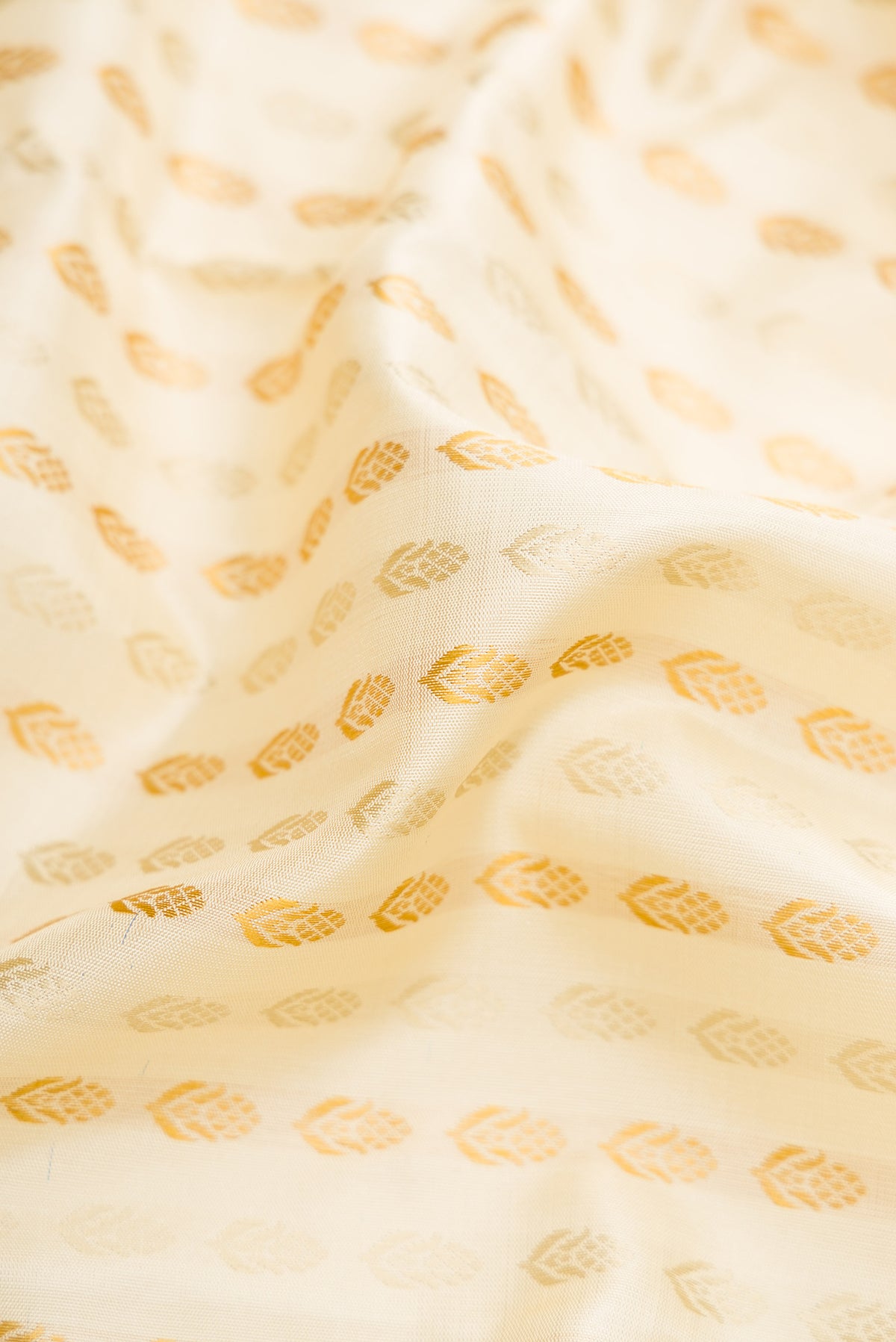 Close up of Pure Silk Pure Zari Off White Dual Tone Kanchipuram Saree with Zari Butta on the body and Zari And Thread Border.  displaying folds