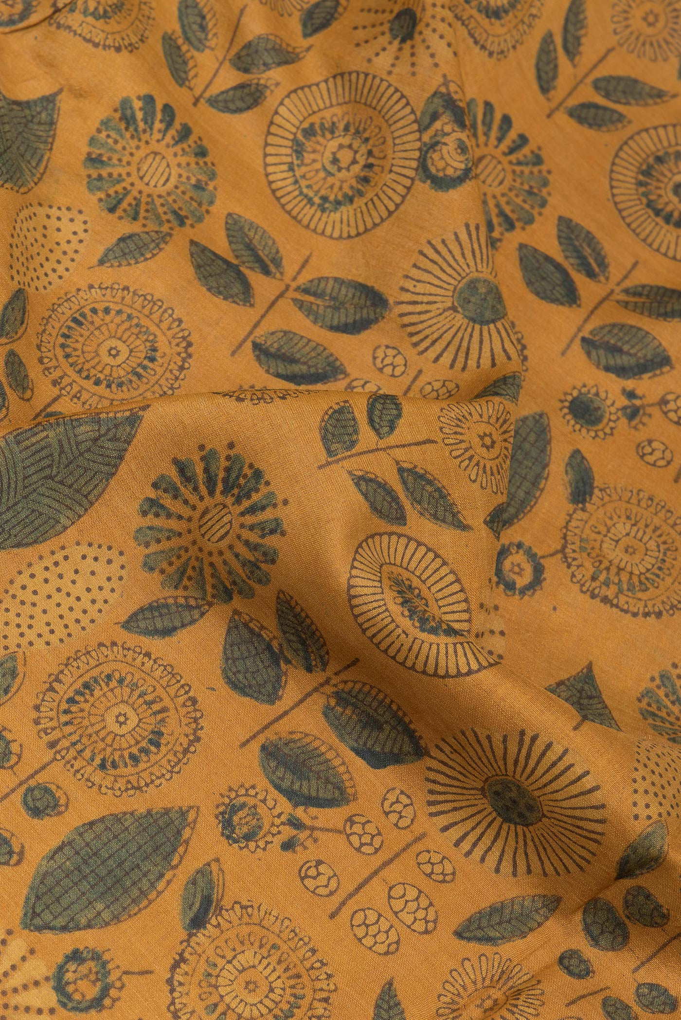 Close up of Mustard Tussar Silk Saree with Printed design on the body and Zari Border.  displaying folds