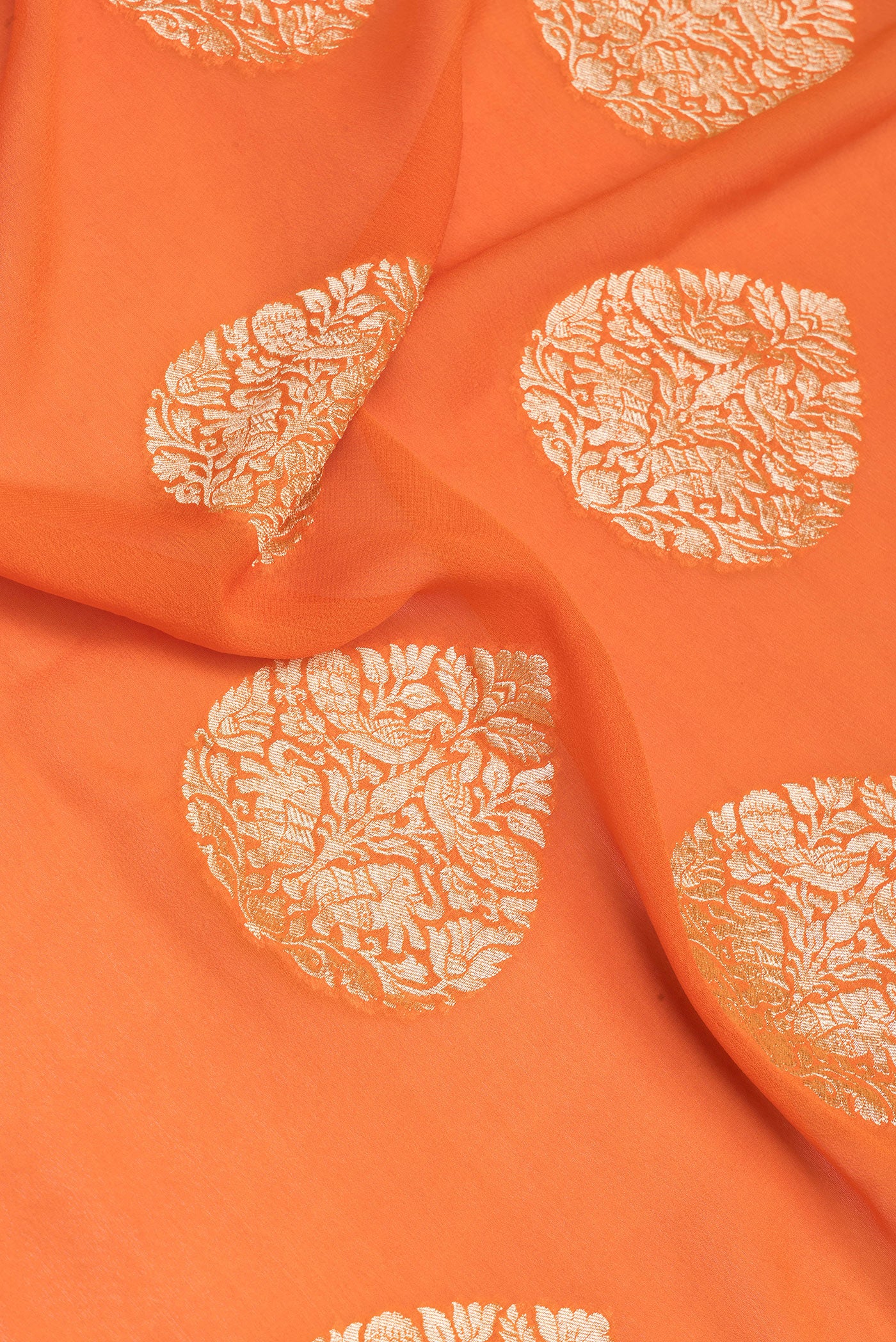 Close up of Orange Banarasi Georgette Saree with Zari Butta on the body and Zari Border.  displaying folds