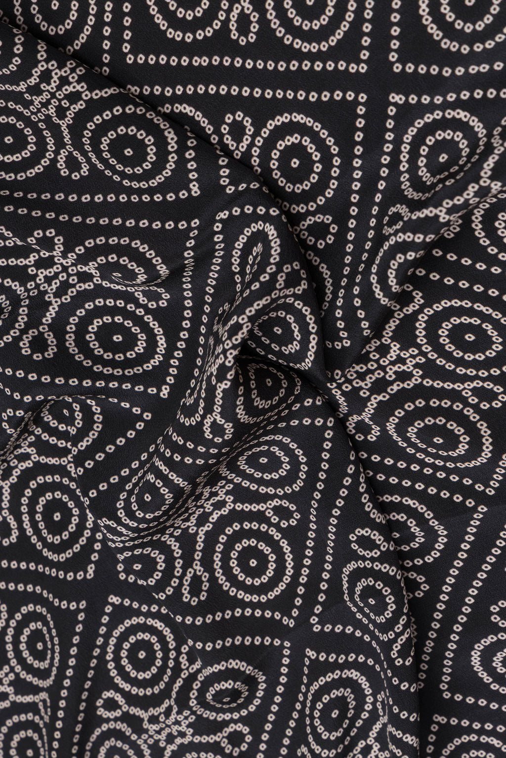 Close up of Black Crepe Saree with Bandhani Print on the body and Printed Border.  displaying folds