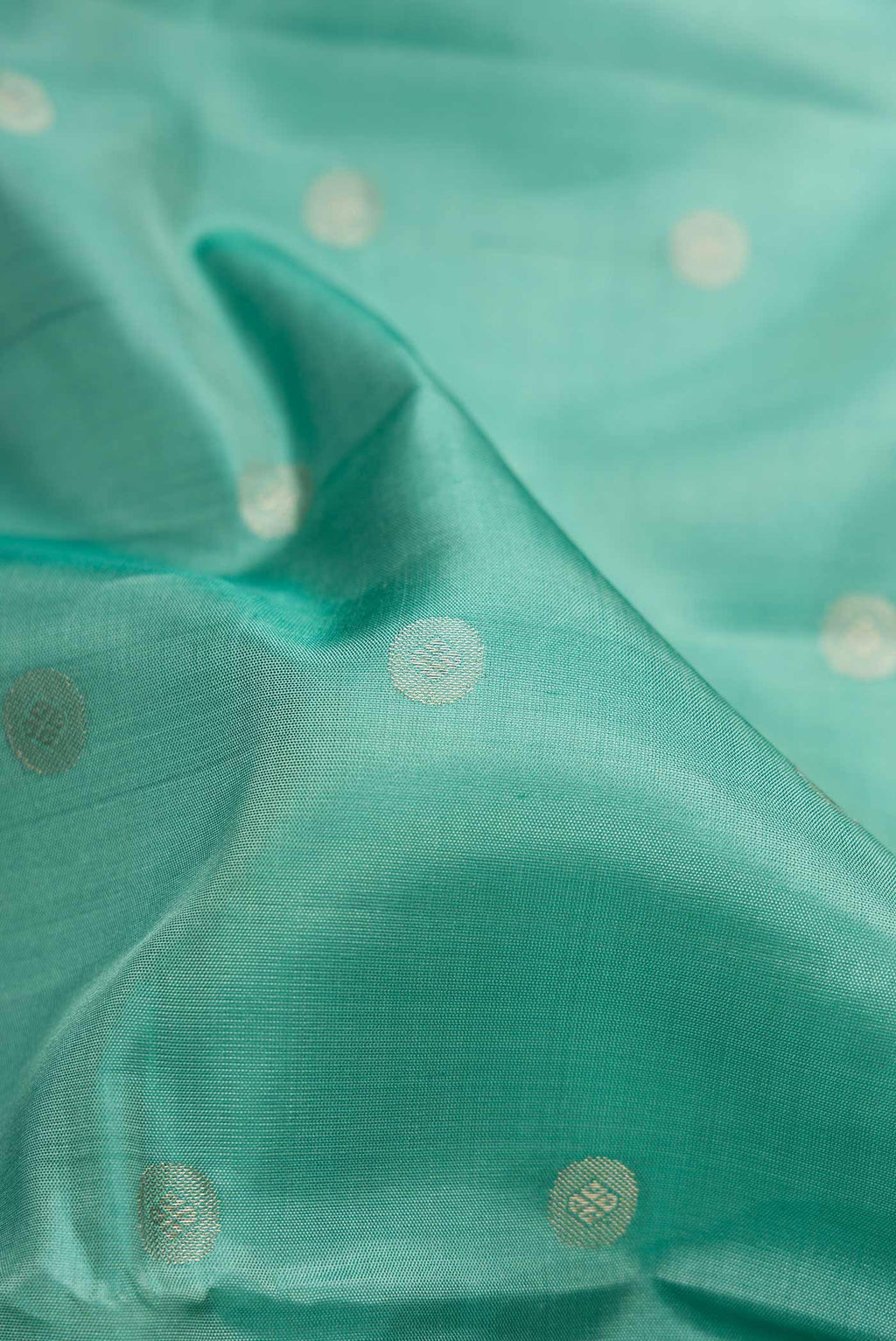Close up of Green Dual Tone Soft Silk Saree with Zari Butta on the body and Zari Border.  displaying folds