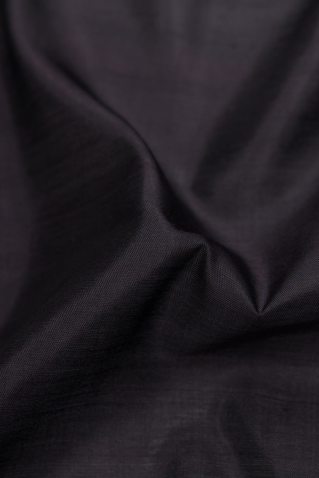 Close up of Black Dual Tone Rajkot Patola Silk Saree with Plain Body and Ikat Border displaying folds