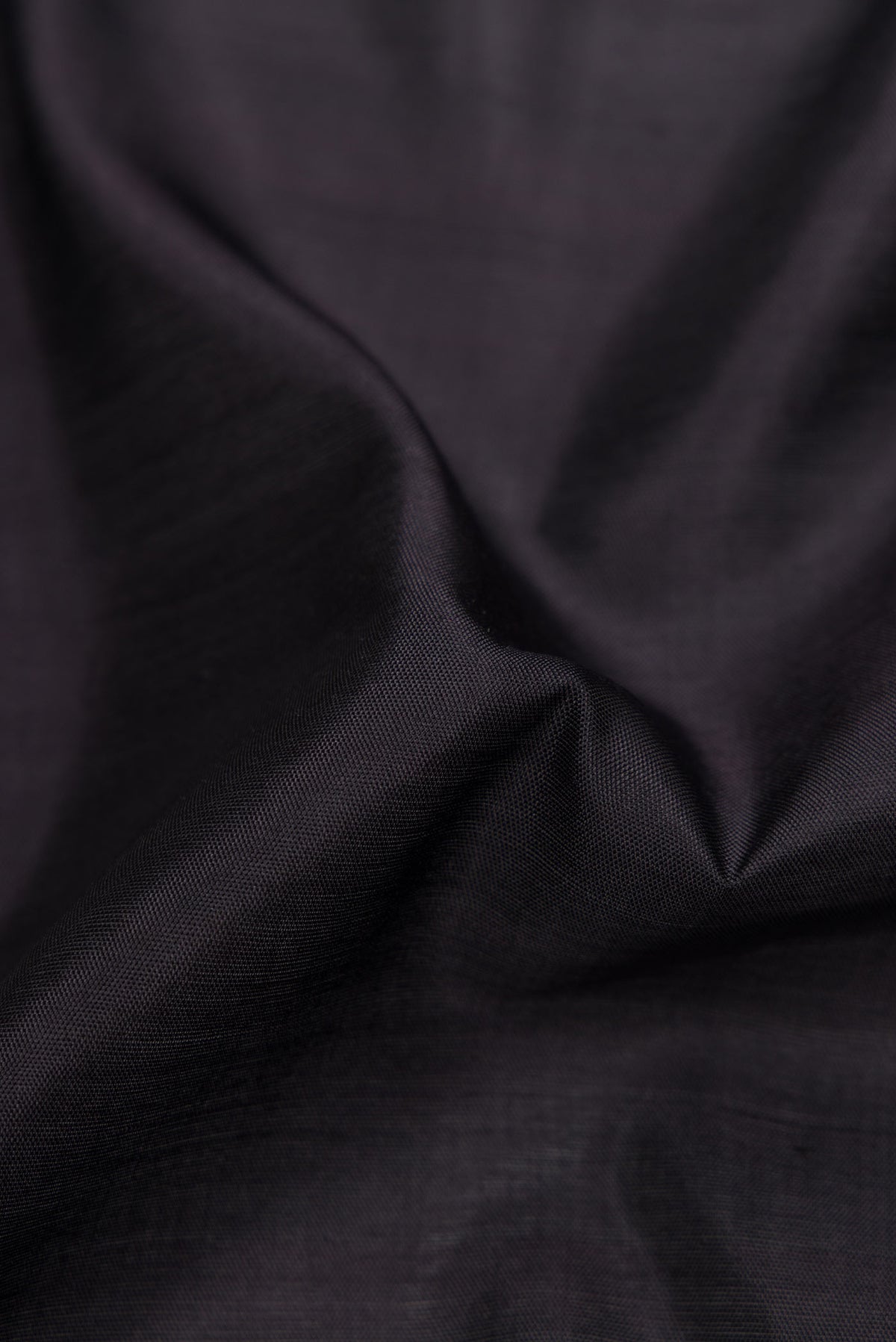 Close up of Black Dual Tone Rajkot Patola Silk Saree with Plain Body and Ikat Border displaying folds
