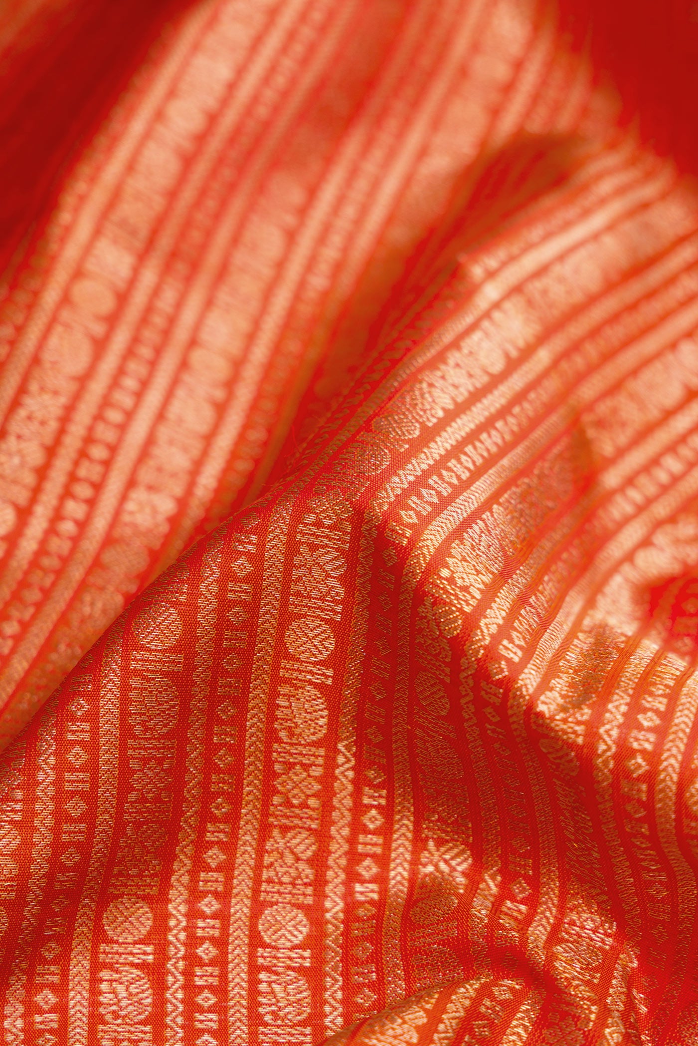 Close up of Orange Kanjivaram Silk Saree with Zari Brocade on the body and Zari Border.  displaying folds
