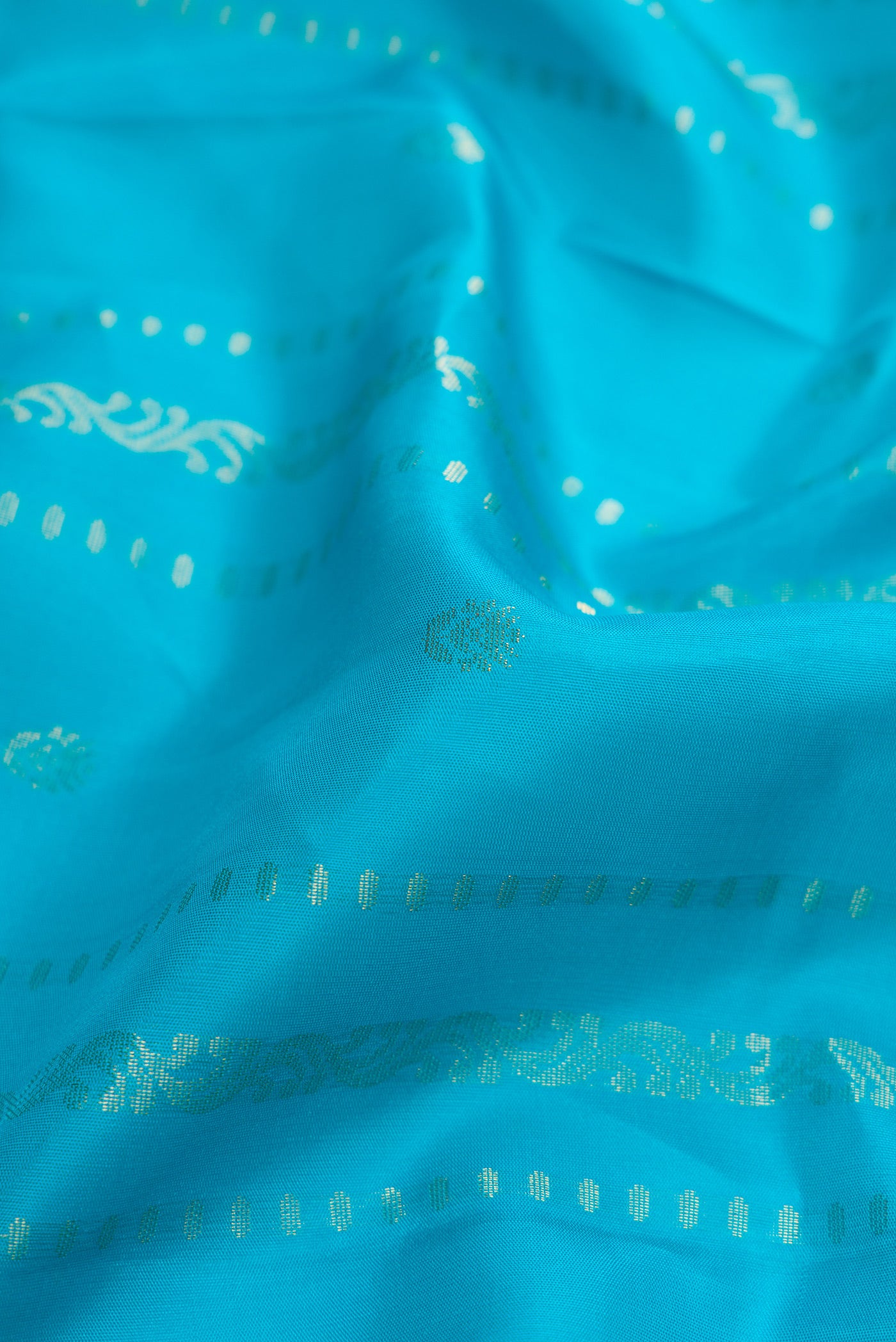 Close up of Sky Blue Dual Tone Soft Silk Saree with Zari Butta on the body and Zari Border.  displaying folds