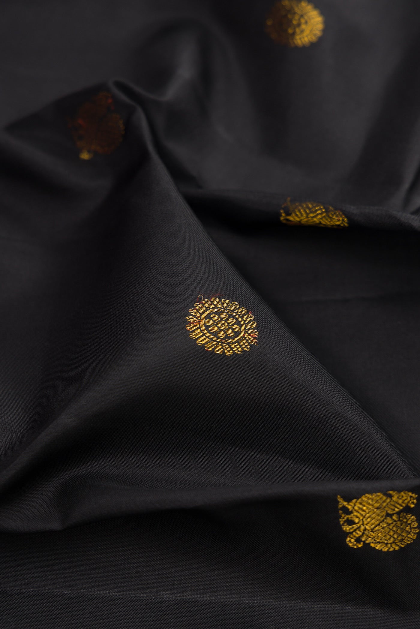 Close up of Black Kanjivaram Silk Saree with Zari Butta on the body and Zari Border.  displaying folds