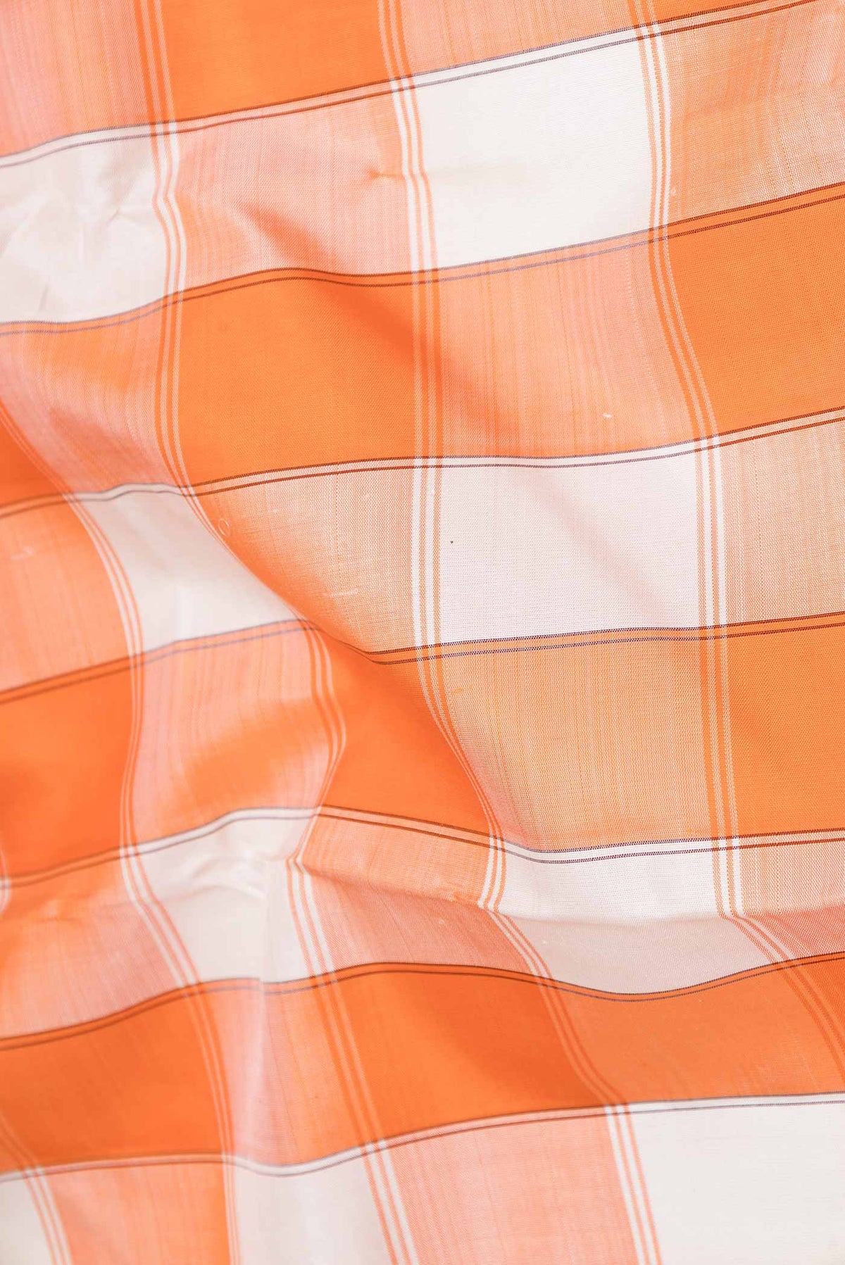 Close up of Off white and Orange Color Kanchipuram Saree with Checked design on the body and Zari Border displaying folds