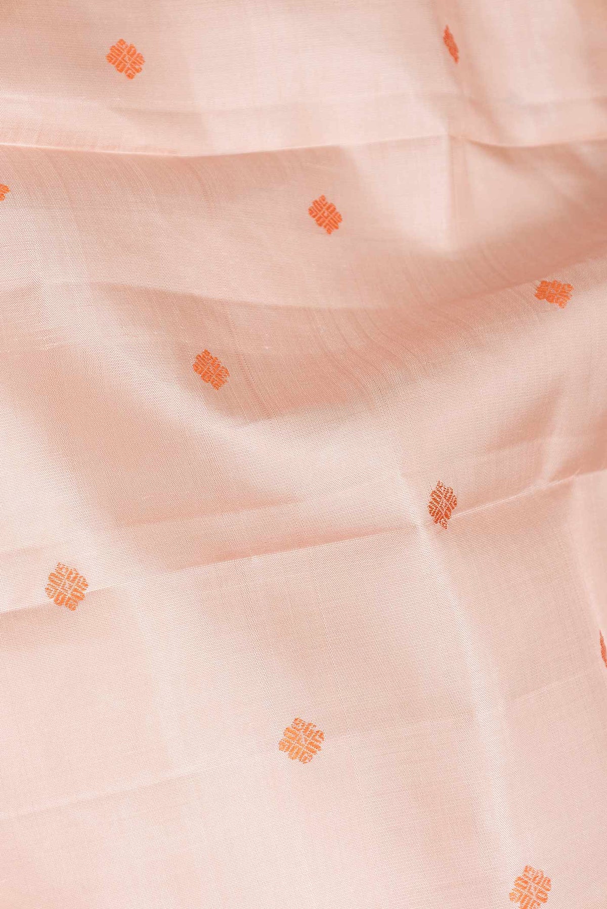 Close up of Peach Dual Tone Kanchipuram Saree with Thread Butta on the body and Zari Border displaying folds