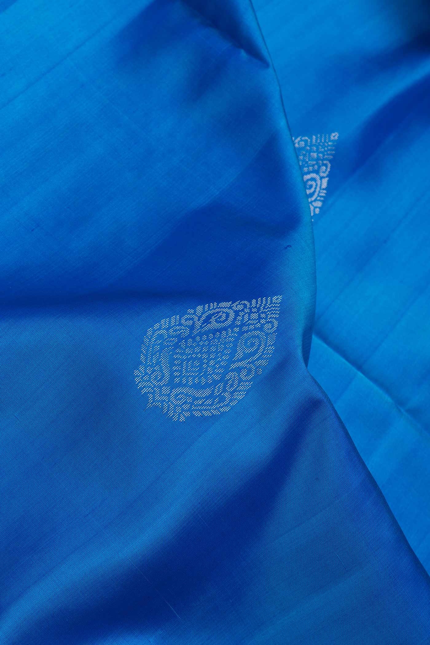 Close up of Peacock Blue Dual Tone Soft Silk Saree with Zari Butta on the body and Zari Border.  displaying folds