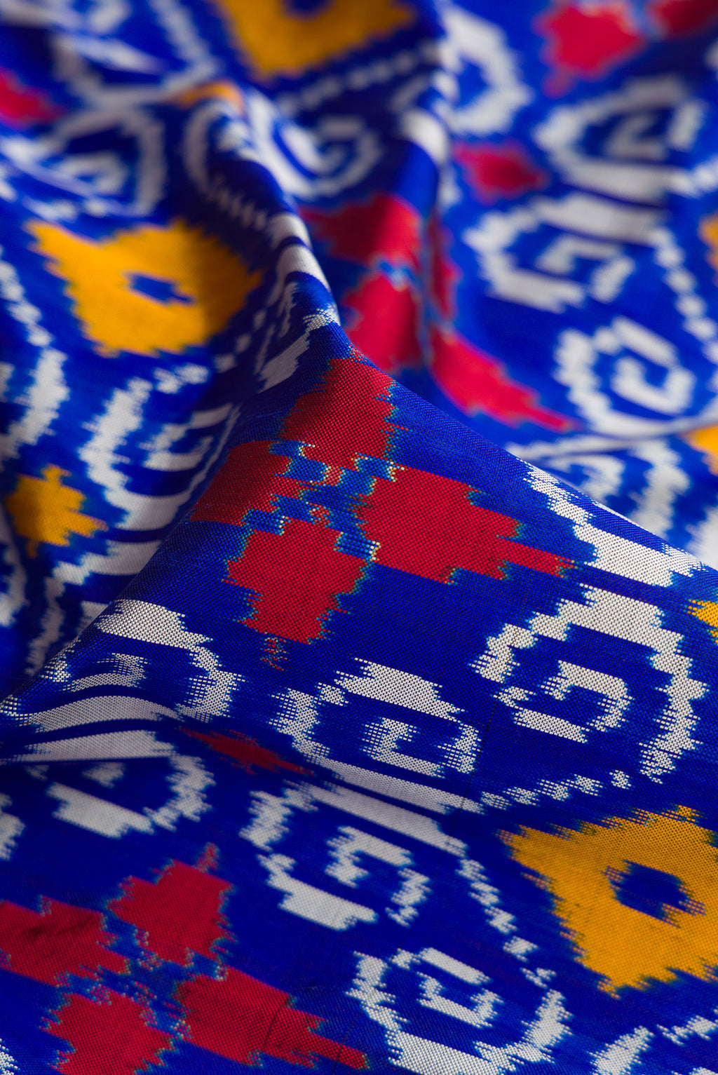 Close up of Navy Blue Dual Tone Double Ikat Saree with Ikat Print on the body and Thread Border.  displaying folds