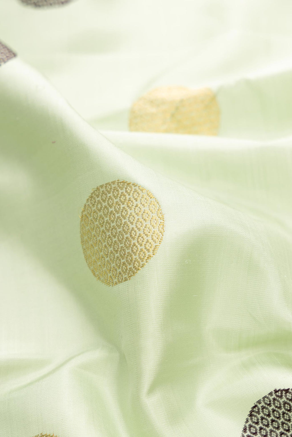 Close up of Pure Silk Pure Zari Pista Green Dual Tone Kanchipuram Saree with Zari And Thread Butta on the body and Zari And Thread Border displaying folds