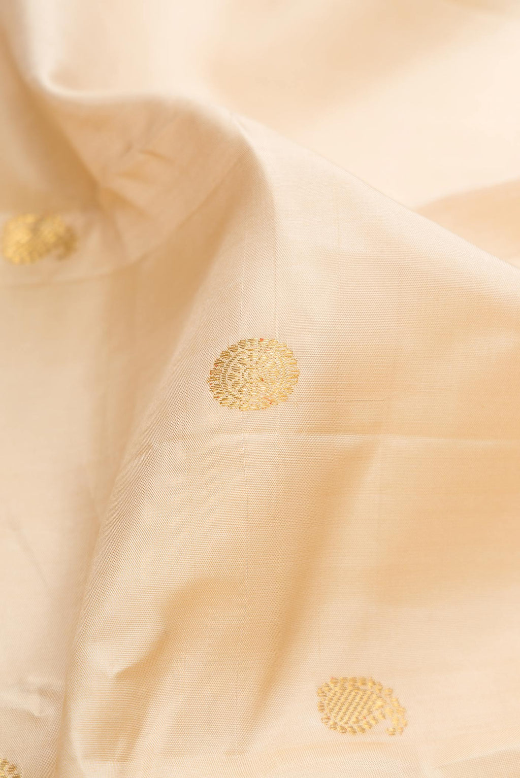 Close up of Cream Kanchipuram Silk Saree with Zari Butta on the body and Zari Border displaying folds
