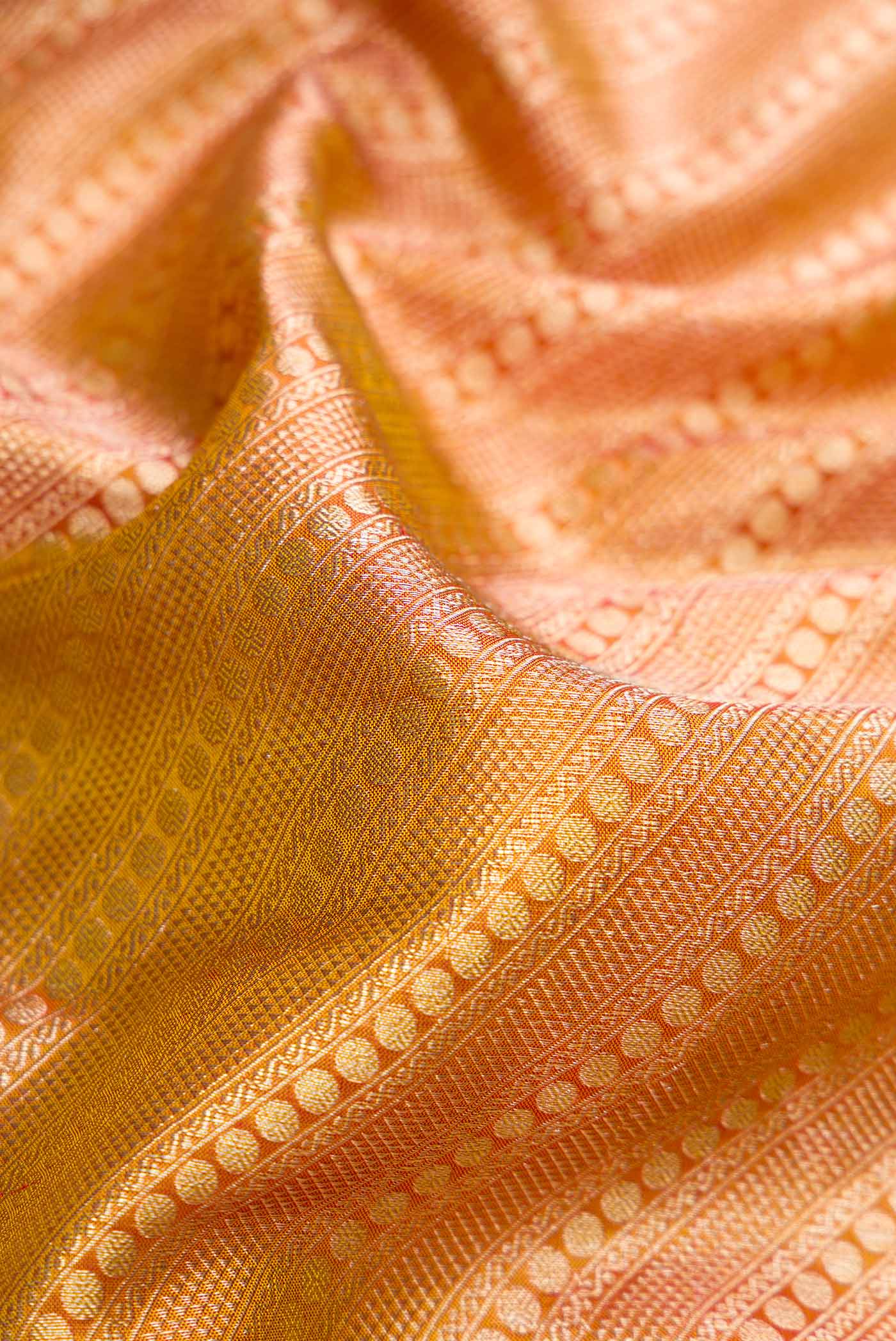 Close up of Gold Dual Tone Kanjivaram Tissue Silk Saree with Zari Brocade on the body and Fancy Border.  displaying folds