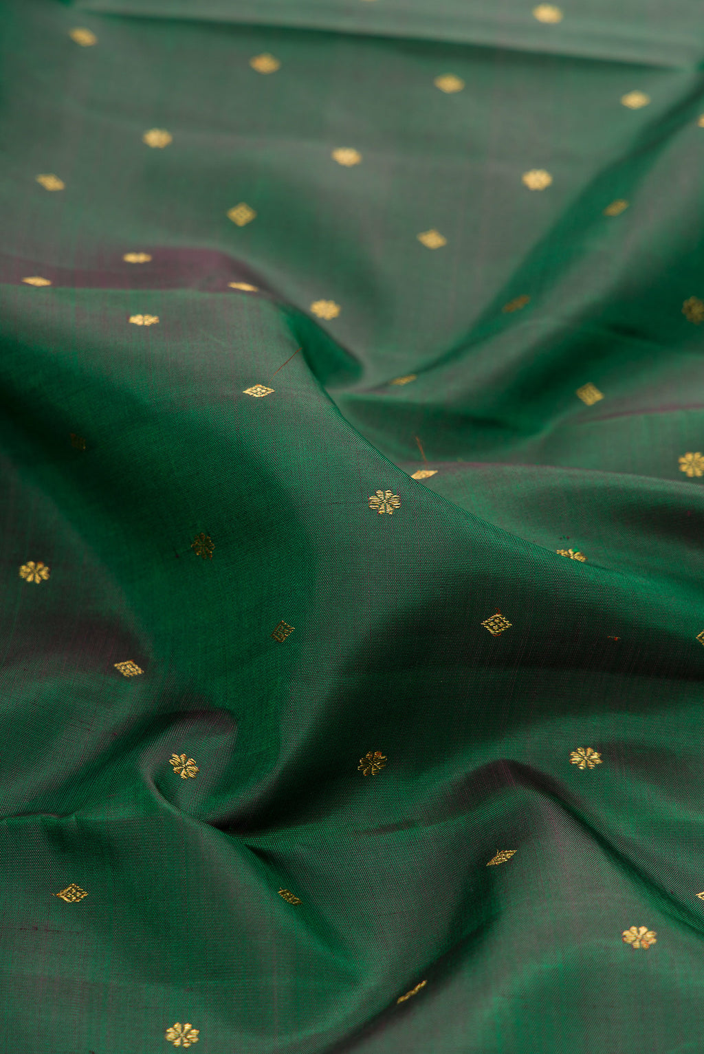 Close up of Pure Silk Pure Zari Green Dual Tone Kanjivaram Saree with Zari Butta on the body and Zari Border.  displaying folds