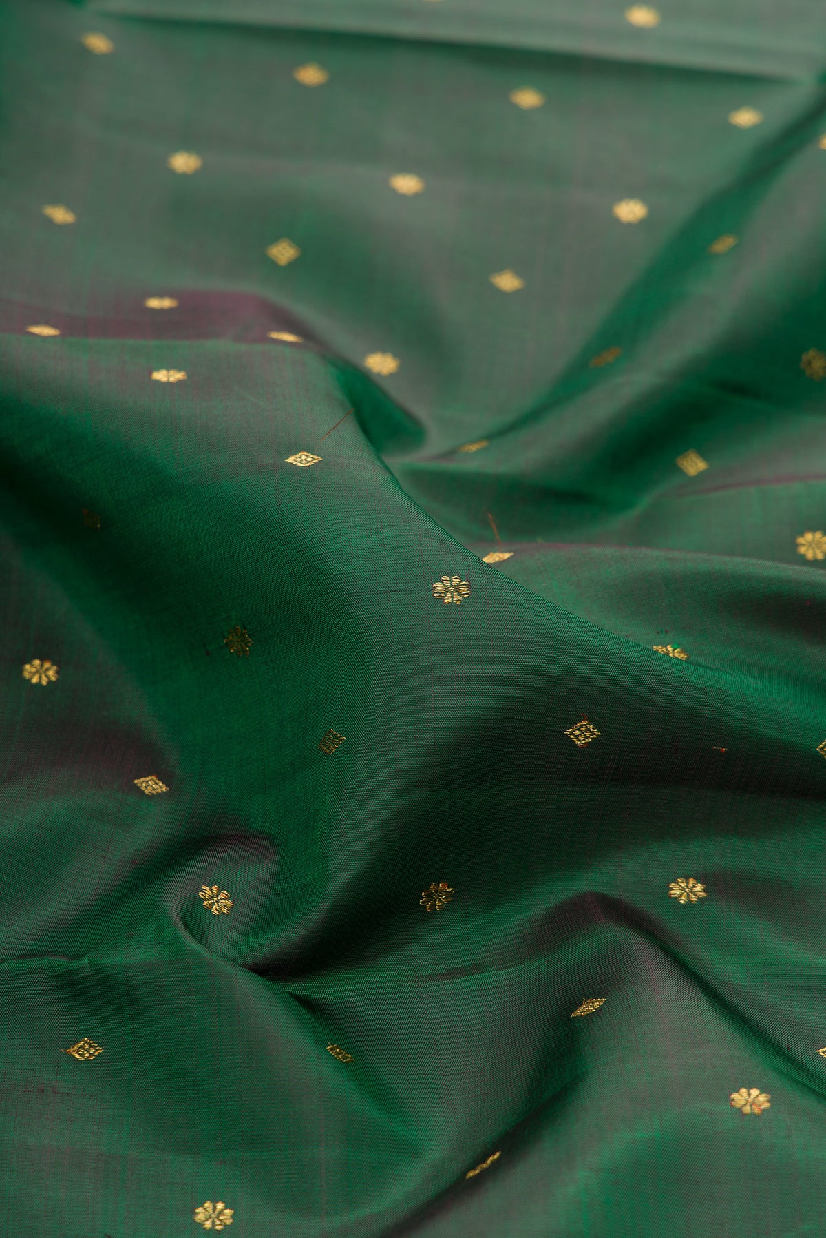 Close up of Pure Silk Pure Zari Green Dual Tone Kanjivaram Saree with Zari Butta on the body and Zari Border.  displaying folds