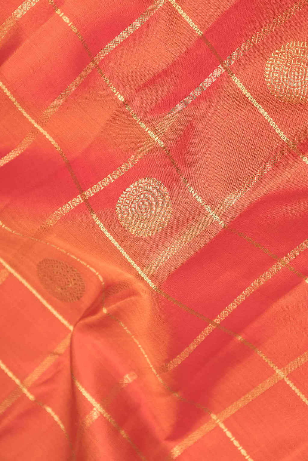 Close up of Pure Silk Pure Zari Orange Dual Tone Kanchipuram Saree with Checked design on the body and Zari Border displaying folds