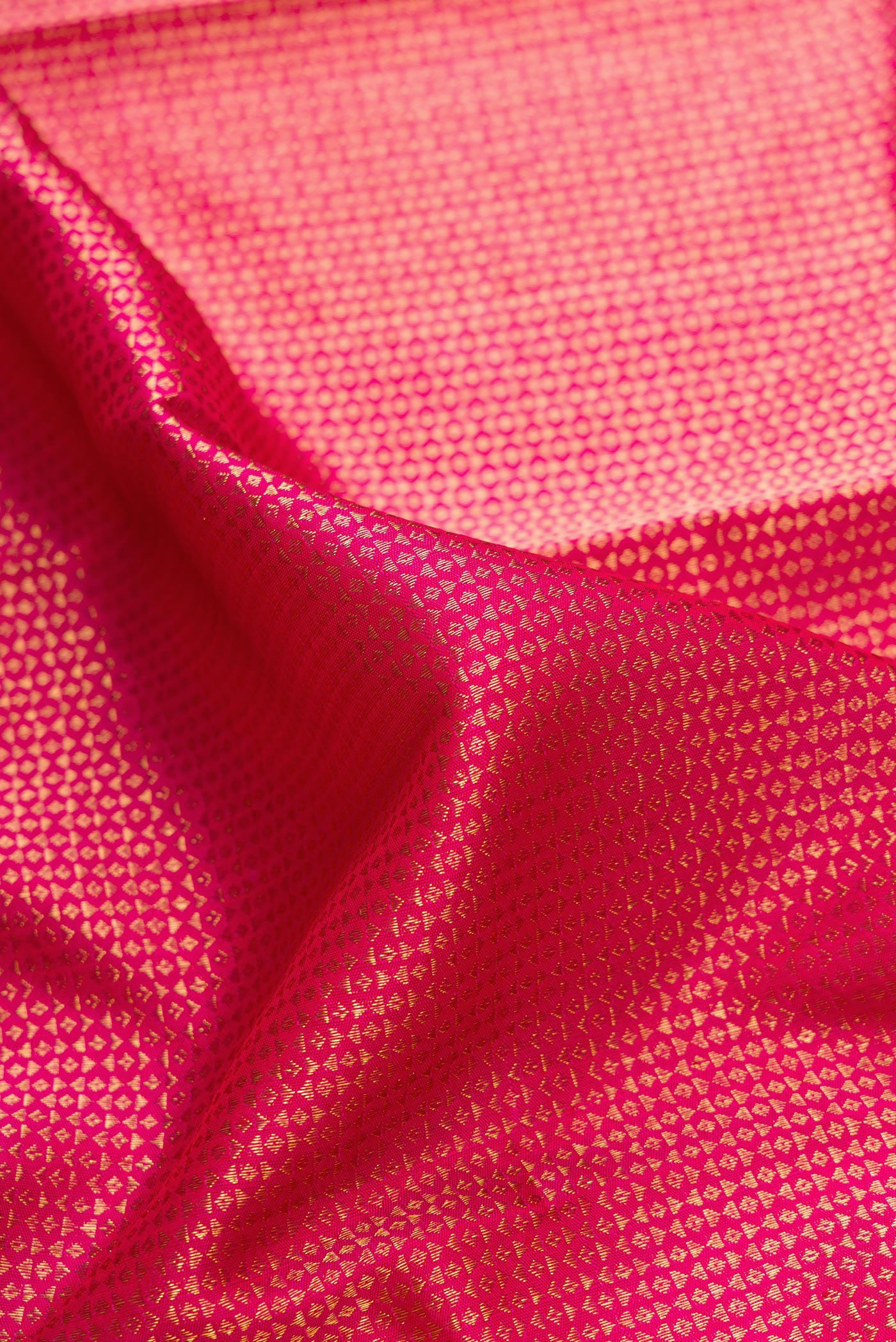 Close up of Rani Pink Dual Tone Kanchipuram Silk Saree with Zari Brocade on the body and Zari Border.  displaying folds