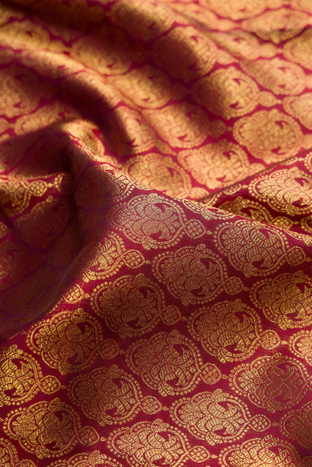 Close up of Pure Silk Pure Zari Maroon Dual Tone Kanjivaram Saree with Zari Brocade on the body and Zari Border.  displaying folds