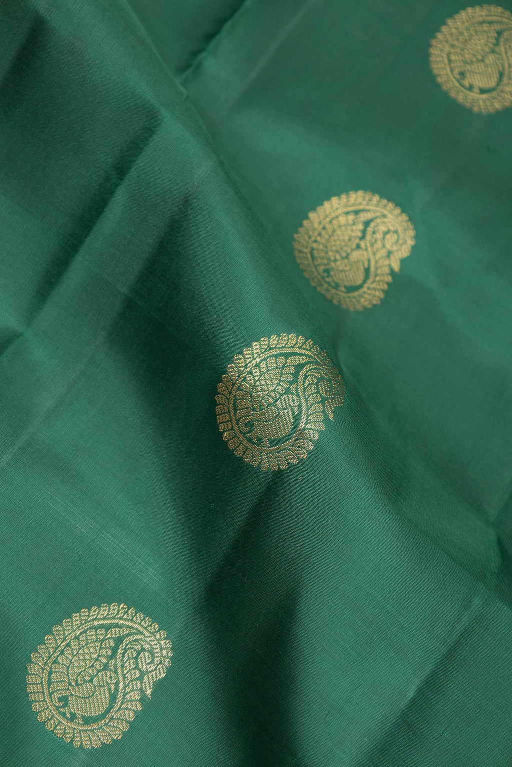 Close up of Pure Silk Pure Zari Bottle Green Dual Tone Kanchipuram Saree with Zari Butta on the body and Zari Border displaying folds