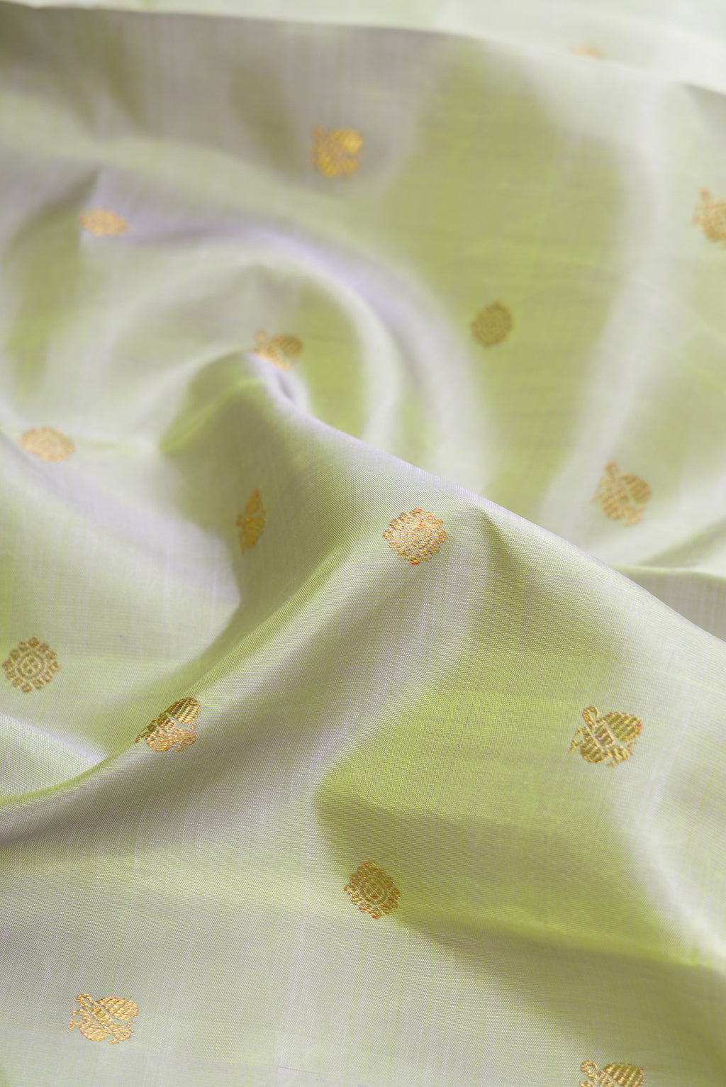 Close up of Pure Silk Pure Zari Pista Green Dual Tone Kanjivaram Saree with Zari Butta on the body and Zari Border.  displaying folds