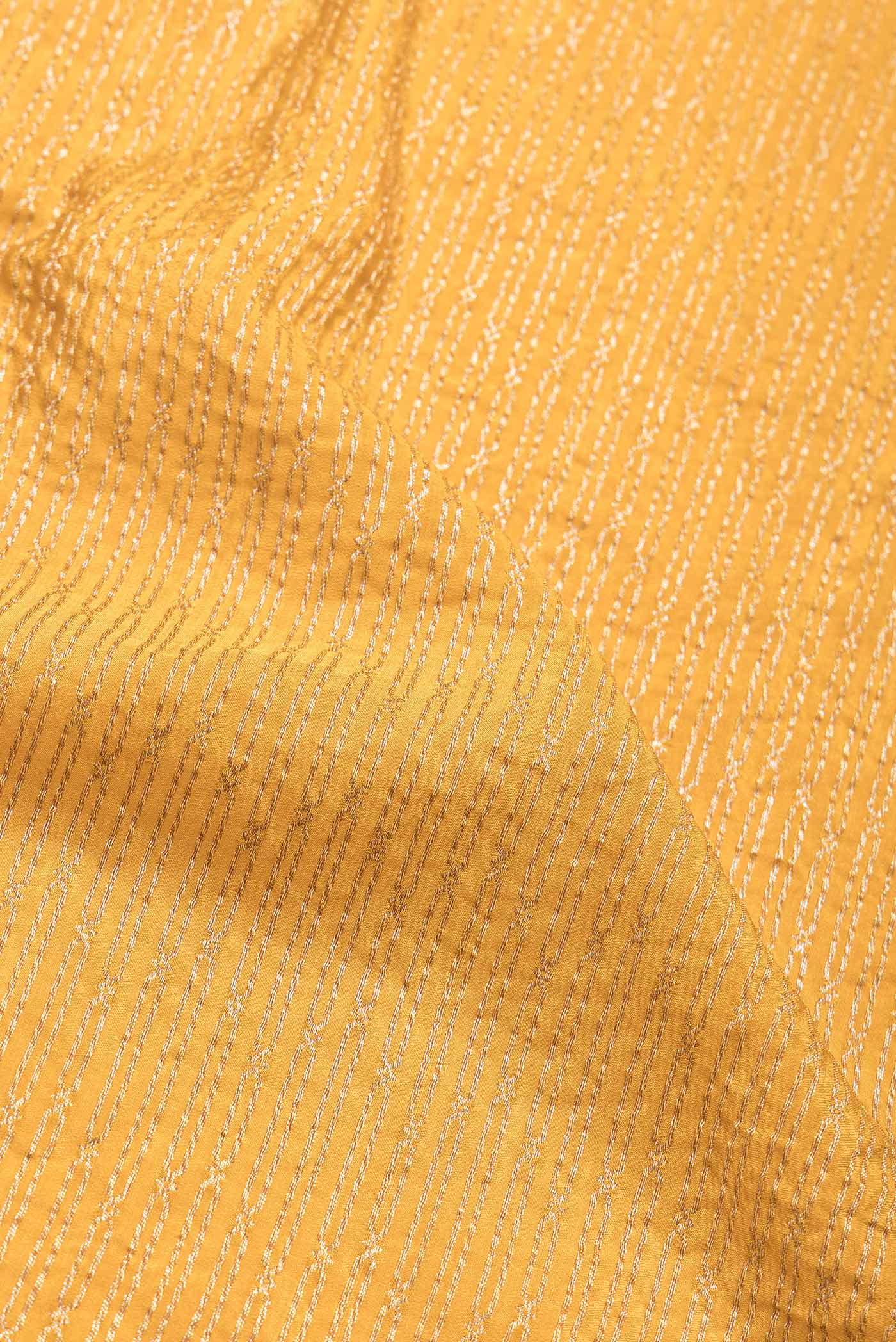 Close up of Mustard Dual Tone Banarasi Georgette Saree with Zari Brocade on the body and Zari Border.  displaying folds